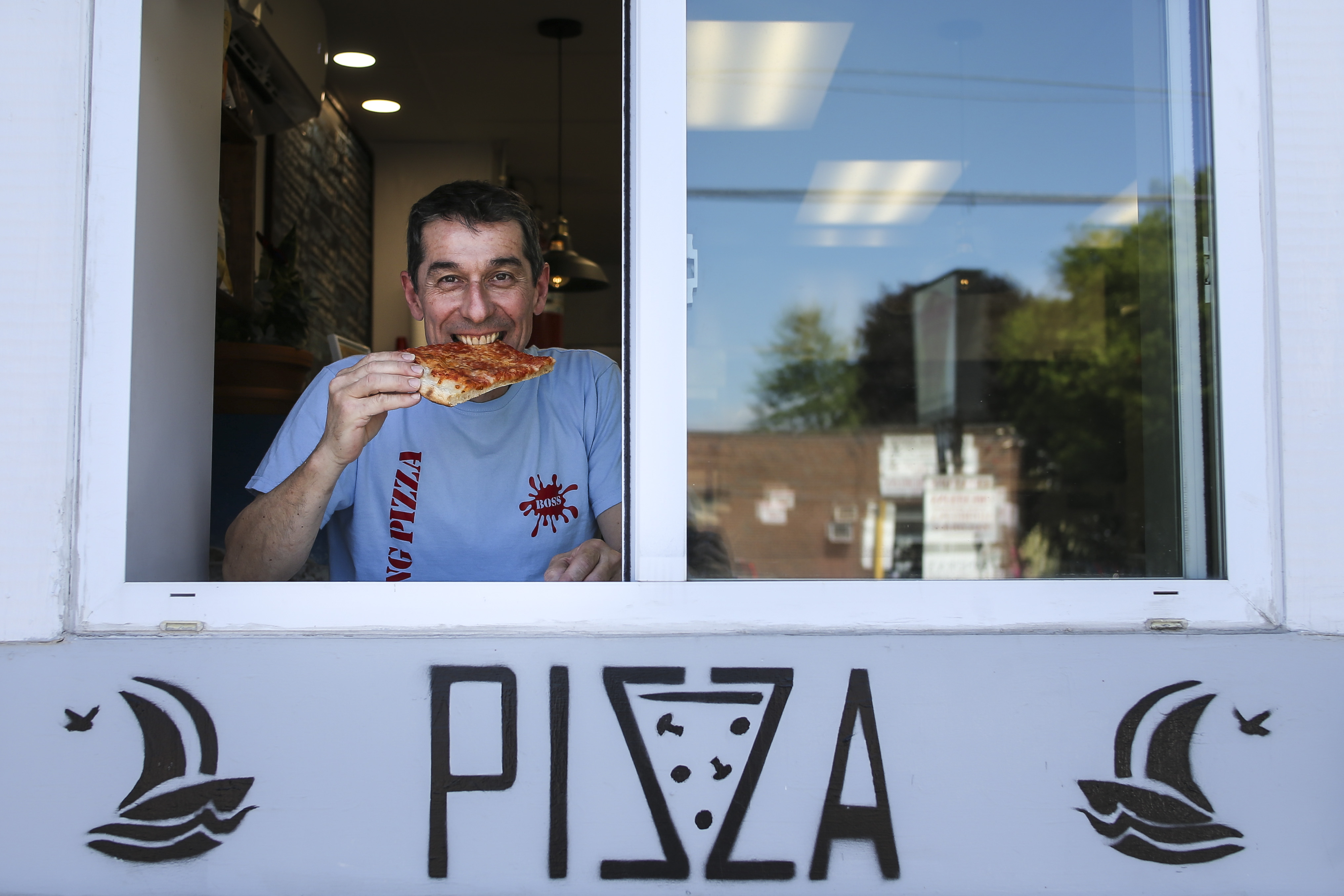 Massimo Ottani takes a bite of Neapolitan-style pizza at his restaurant, The Landing.