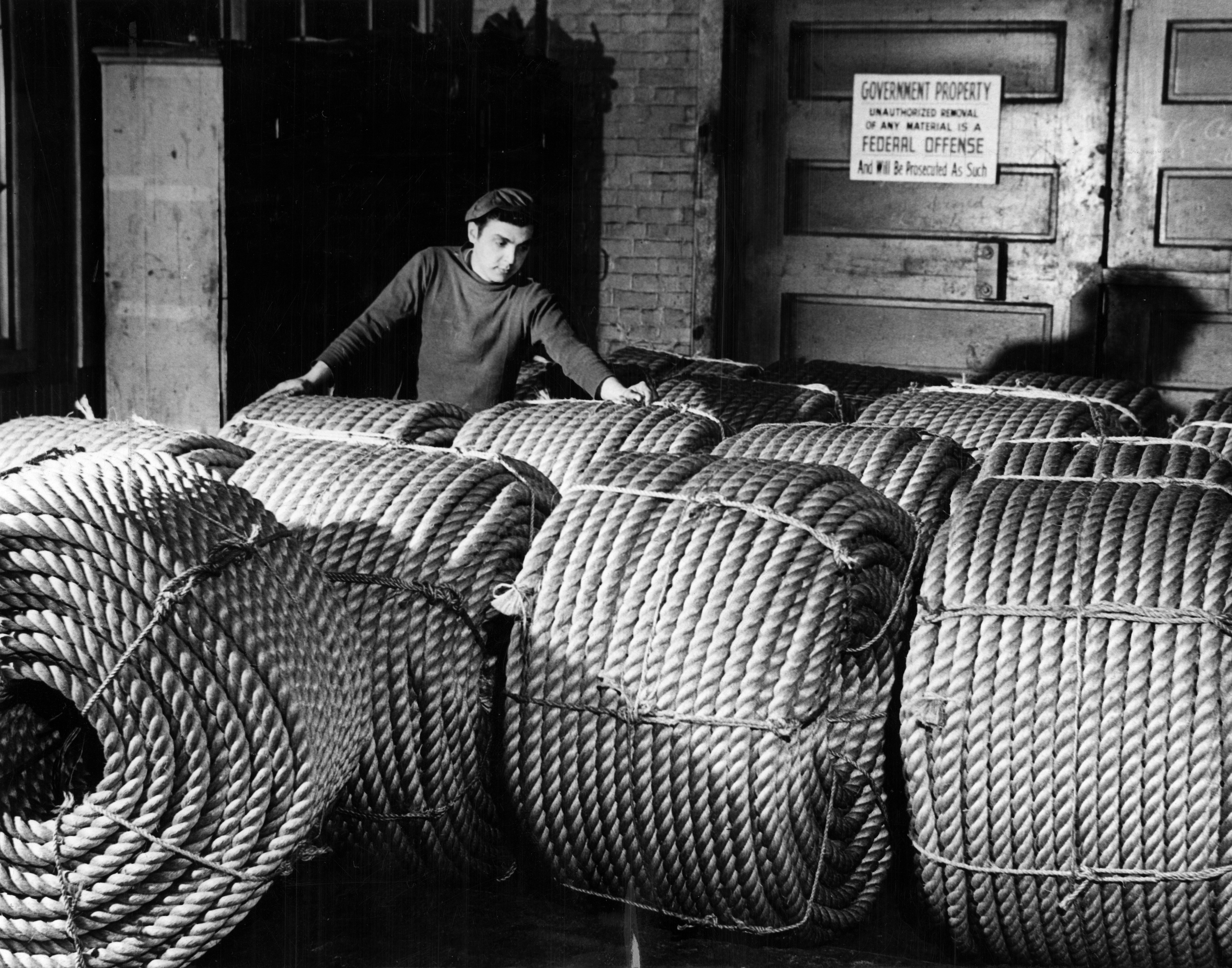 A man checked rolls of six-inch rope, ready for shipment to Naval bases for use aboard fleet ships at the Ropewalk in the Charlestown Navy Yard in Boston.
