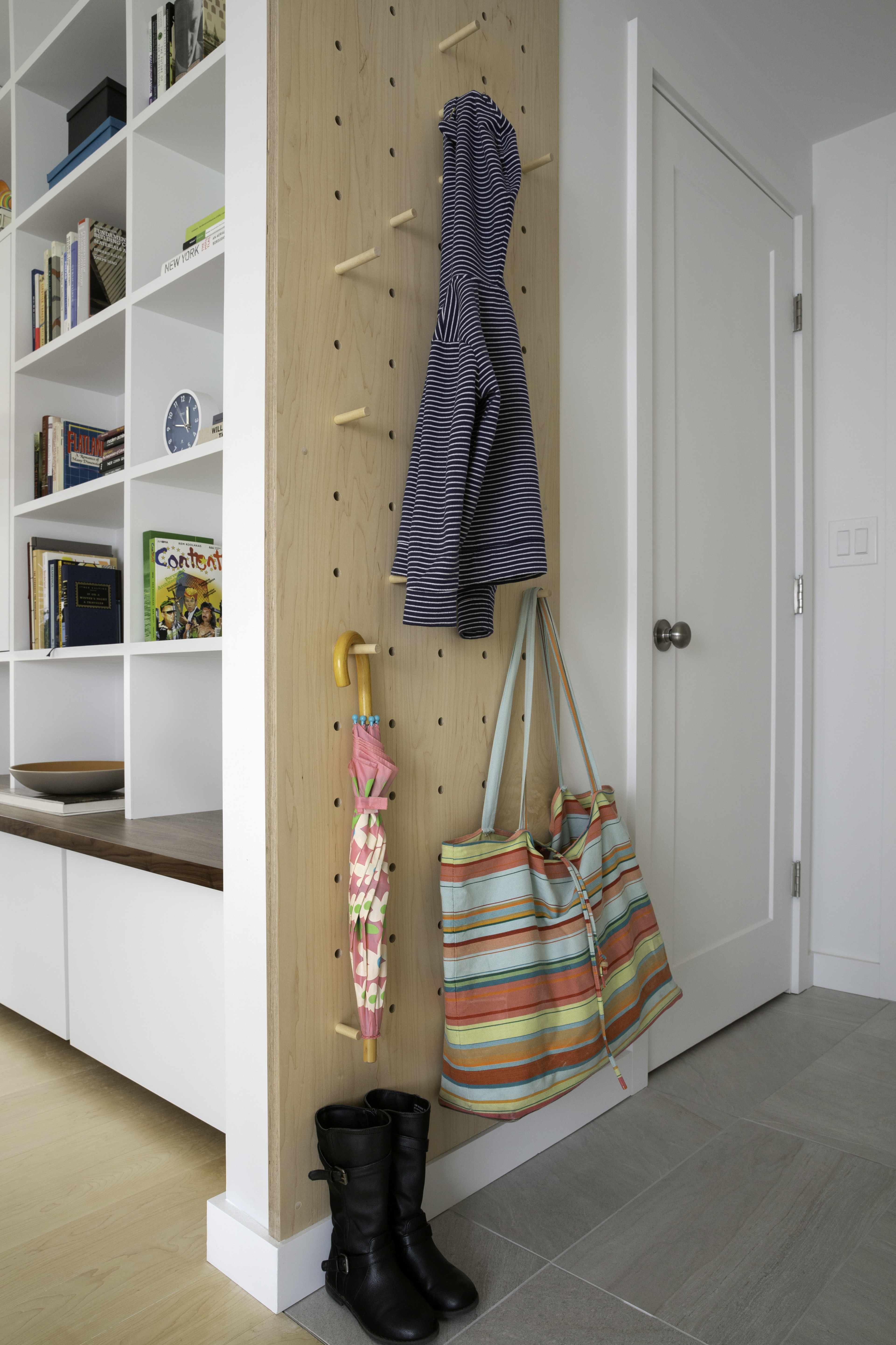 In the side entry from the garage, a custom pegboard panel is an efficient, playful solution for coats and bags. The architects chose large format ceramic floor tile for practicality.