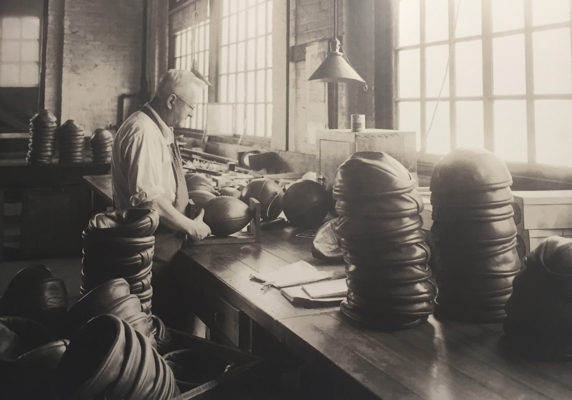 A worker crafts footballs at Draper & Maynard Co. in the early 1900s.