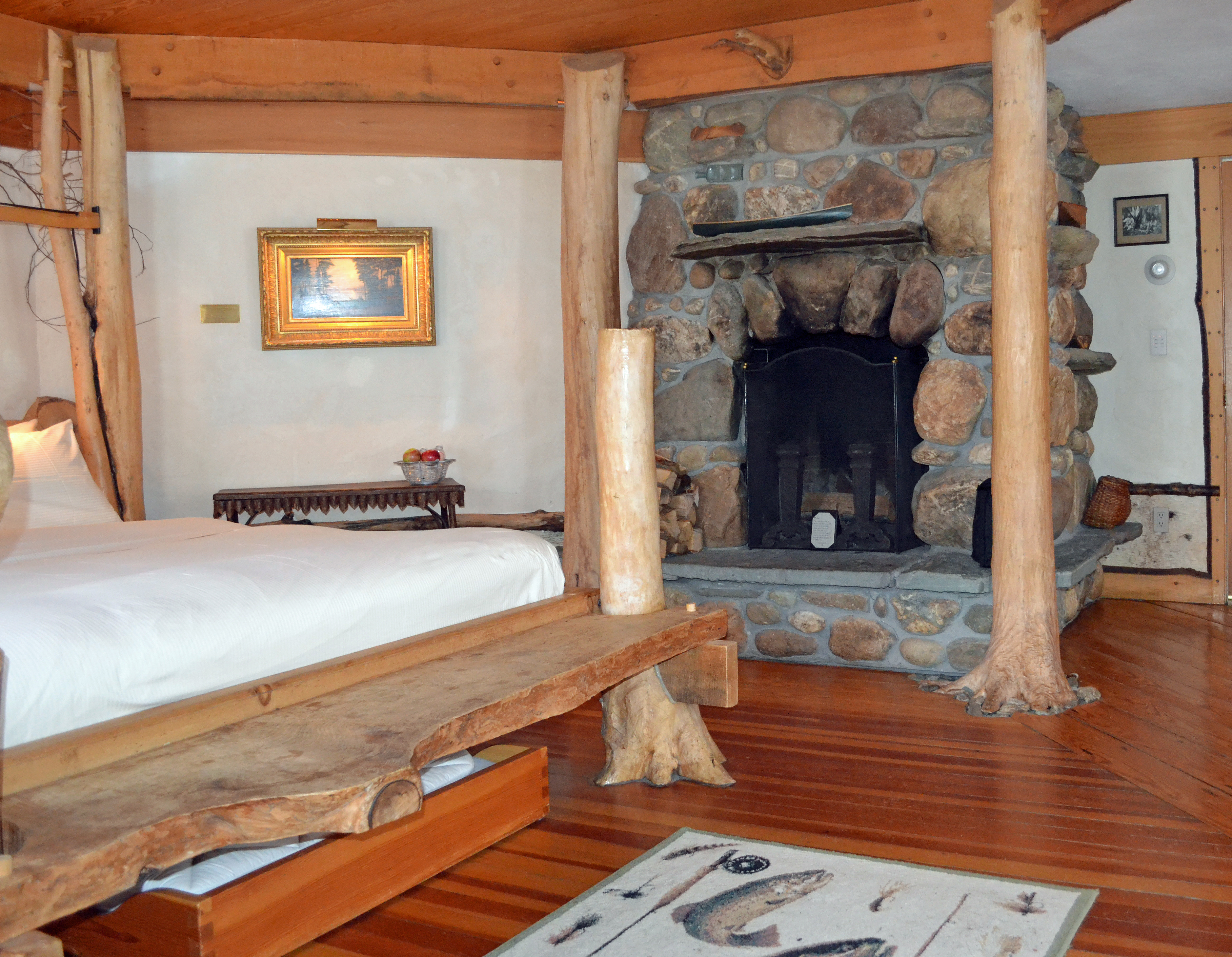 The Trout Room at the Pitcher Inn has a tree-trunk bed frame and river stone fireplace.