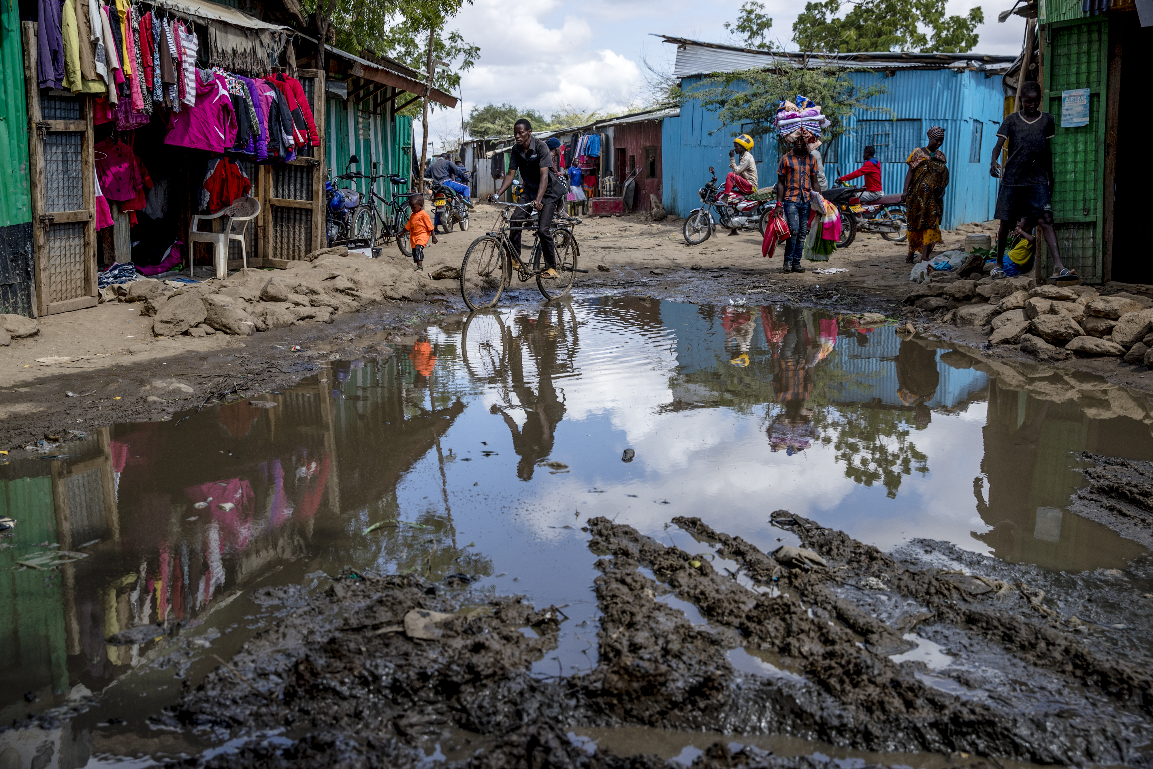 People made their way along a pool of standing water in the UNHCR refugee camp. Even after minor rains, water settles into pools that cause muddy and difficult conditions on roads.