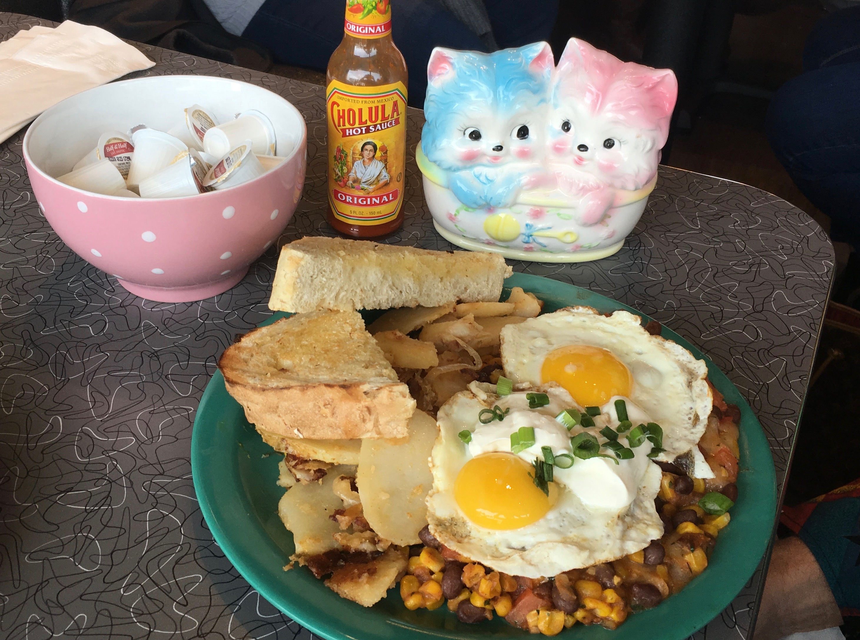 A pair of kittens, hot sauce, and a plate of the "Costa Rican" egg dish at the Friendly Toast.