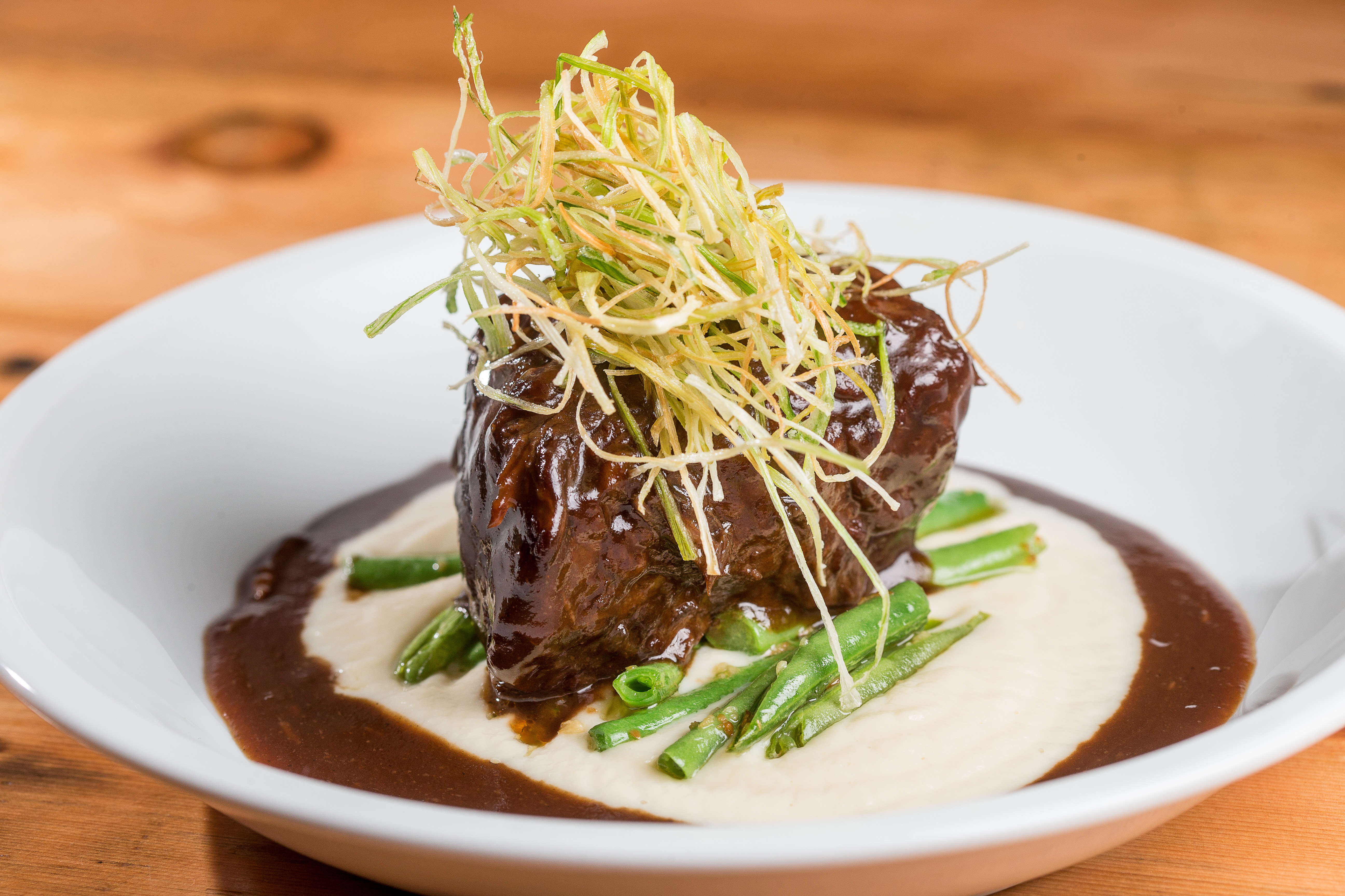 Braised short ribs in a cauliflower puree and served with green beans and fried leeks.
