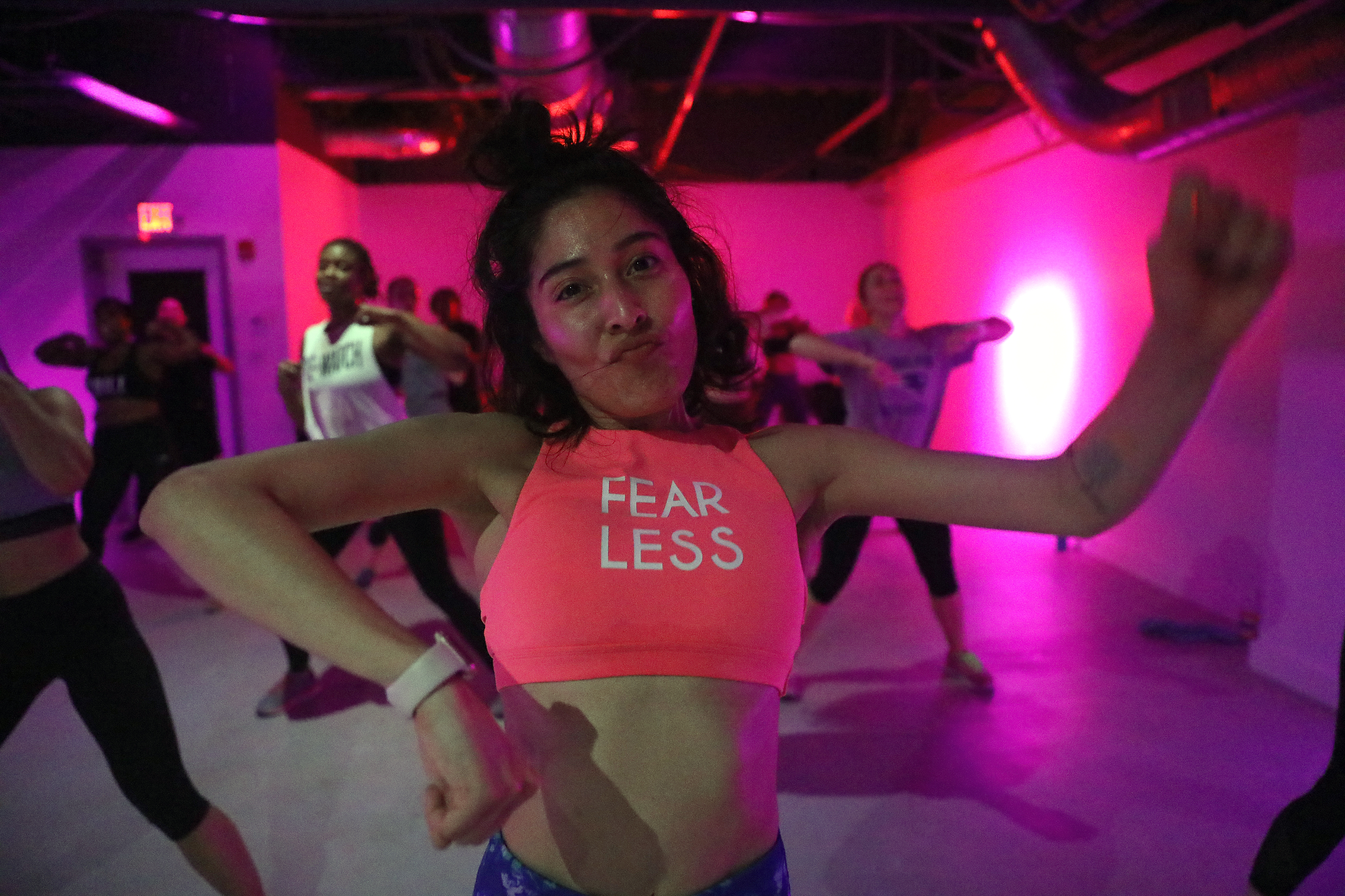 In the front row, 27-year-old Chantal Banuelos shines in a neon orange sports bra that says “Fearless.”