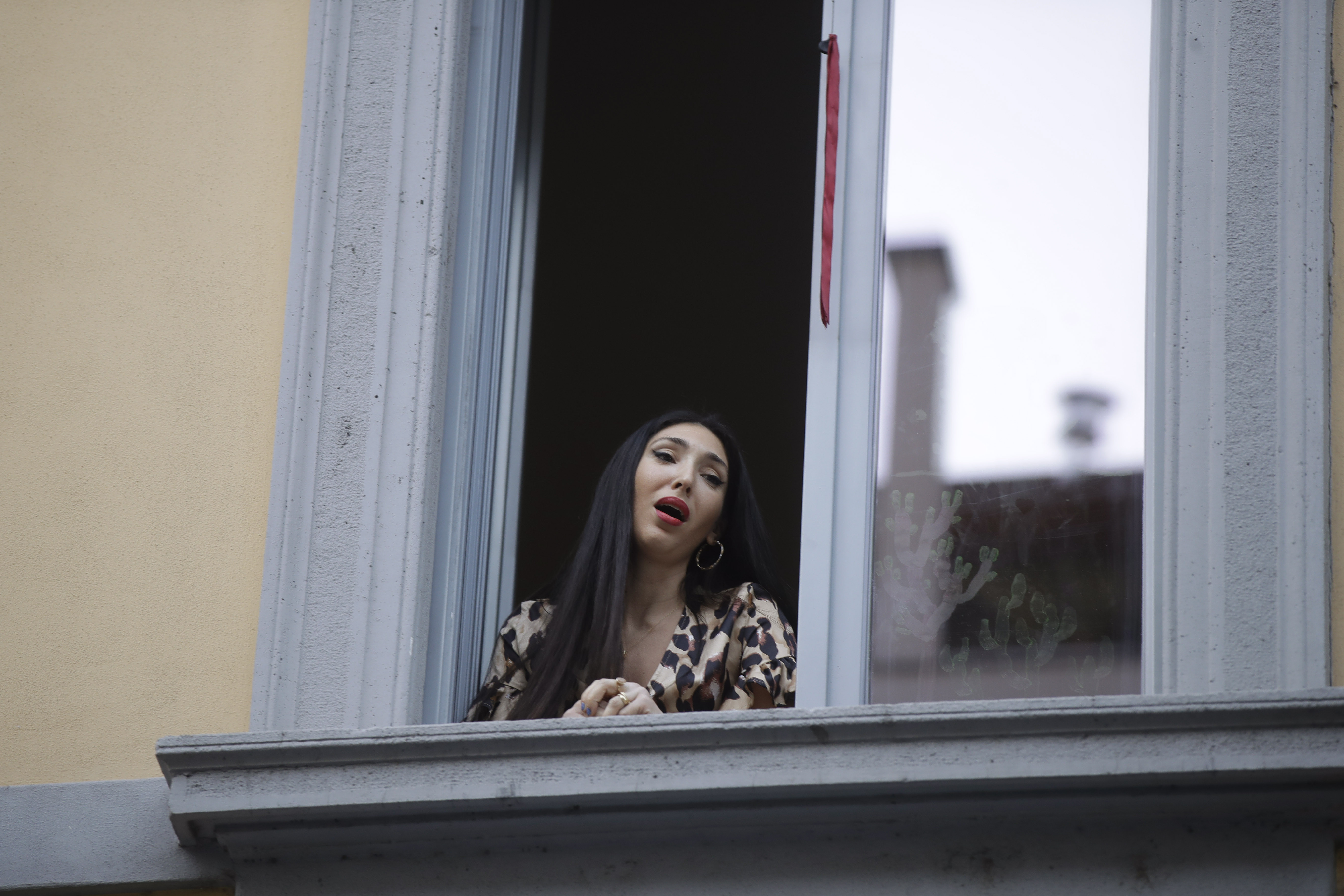 Opera singer Laura Baldassari leans out of her window to sing during a flash mob launched throughout Italy to bring people together and try to cope with the emergency of coronavirus, in Milan, Italy, on March 13.