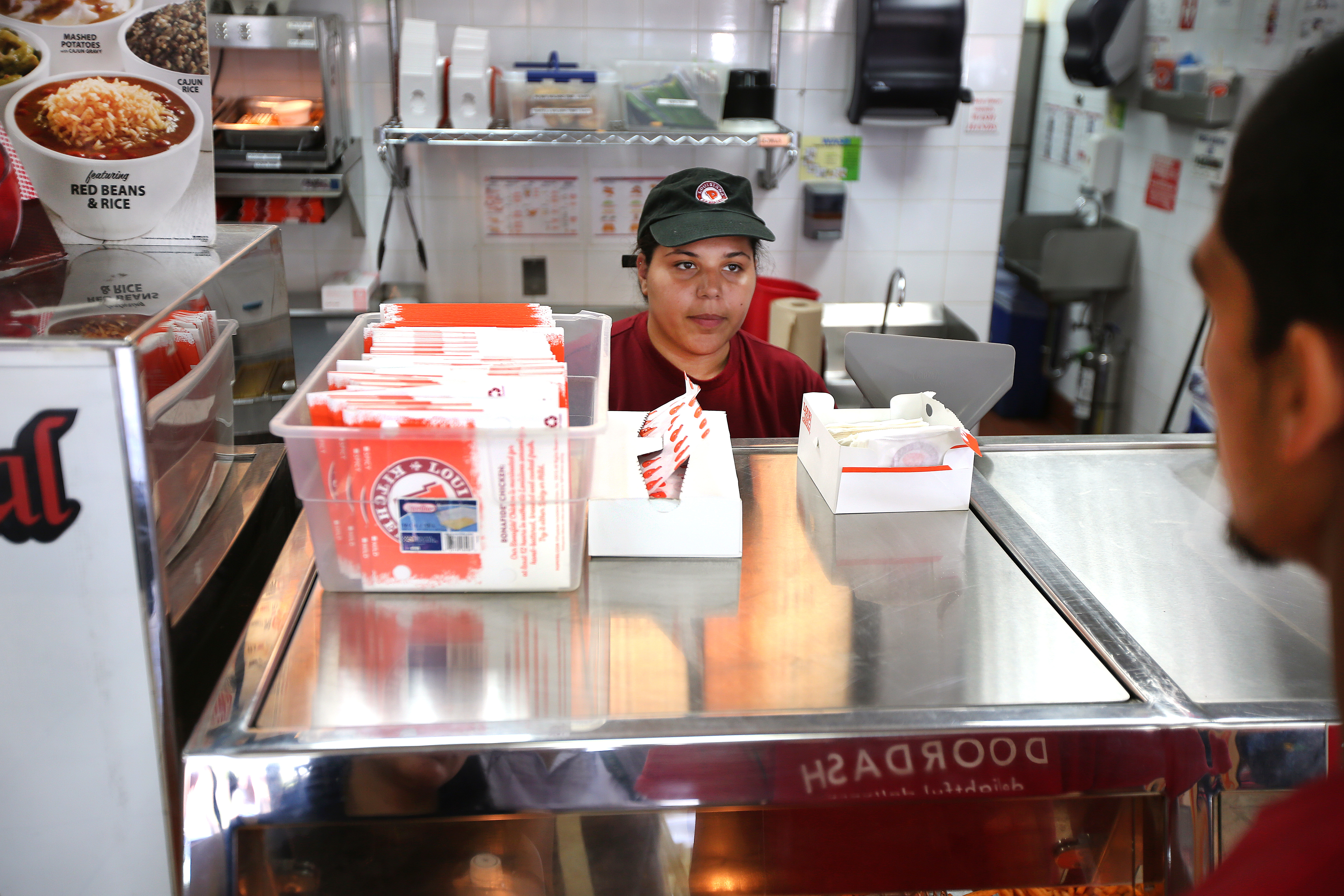 Rita Diaz, a worker at Popeyes, took a customer’s order. UMass Boston research shows that Hispanic women face a wider wage gap, especially in lower-paying jobs, when compared with women of other backgrounds.