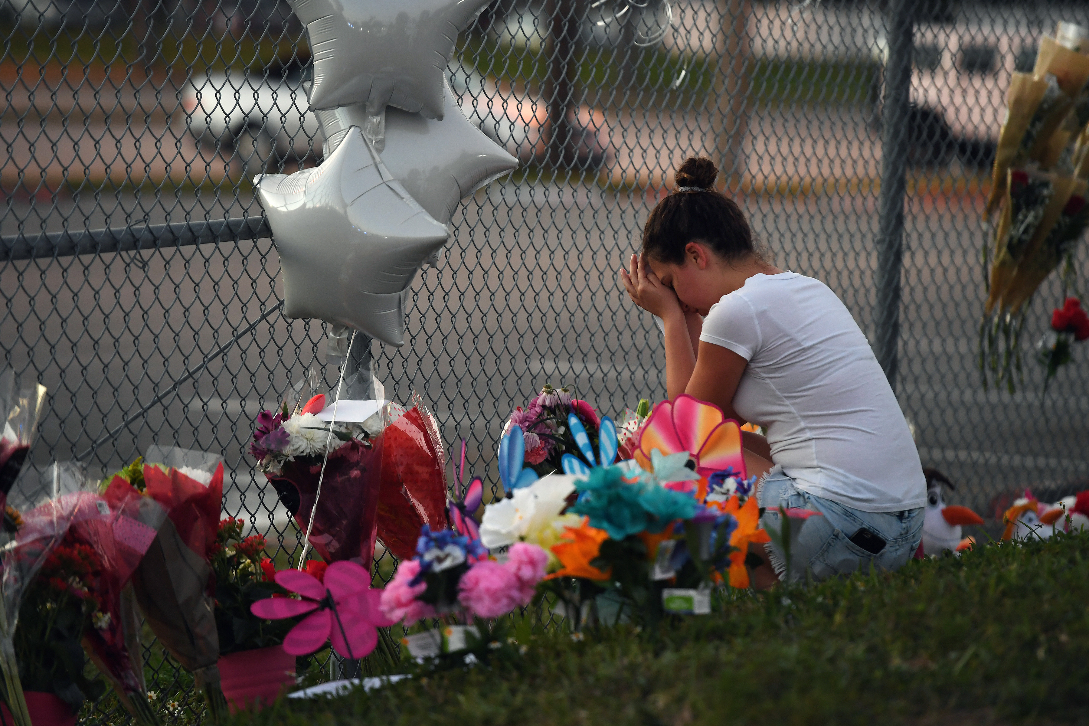 Shana Rosenthal, a student at Marjory Stoneman Douglas High School, kneeled at the fence surrounding the school on Sunday.