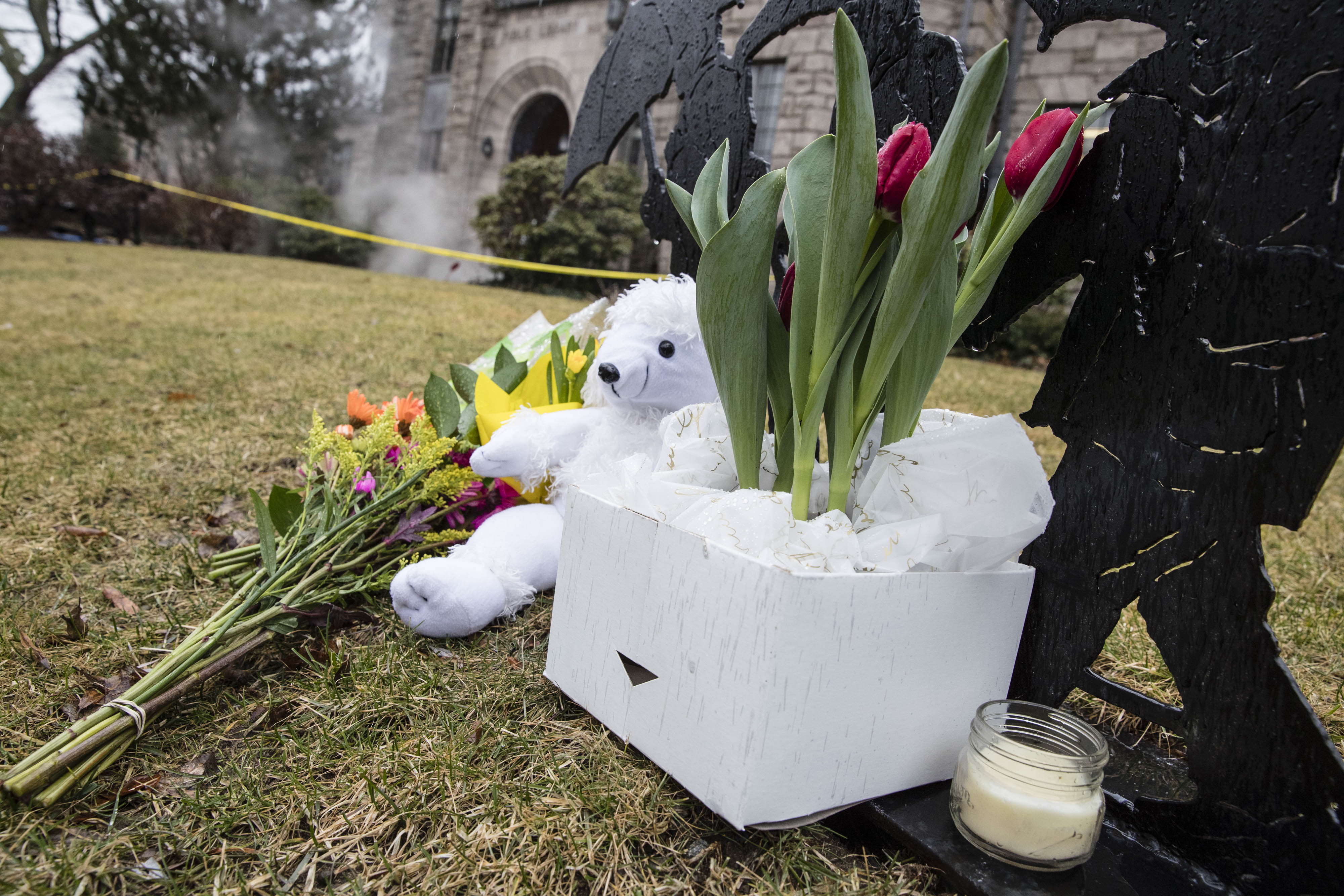 A makeshift memorial sits in the lawn of the Winchester Public Library as a cleaning crew steam cleans the area where Deane Stryker was fatally stabbed Saturday.