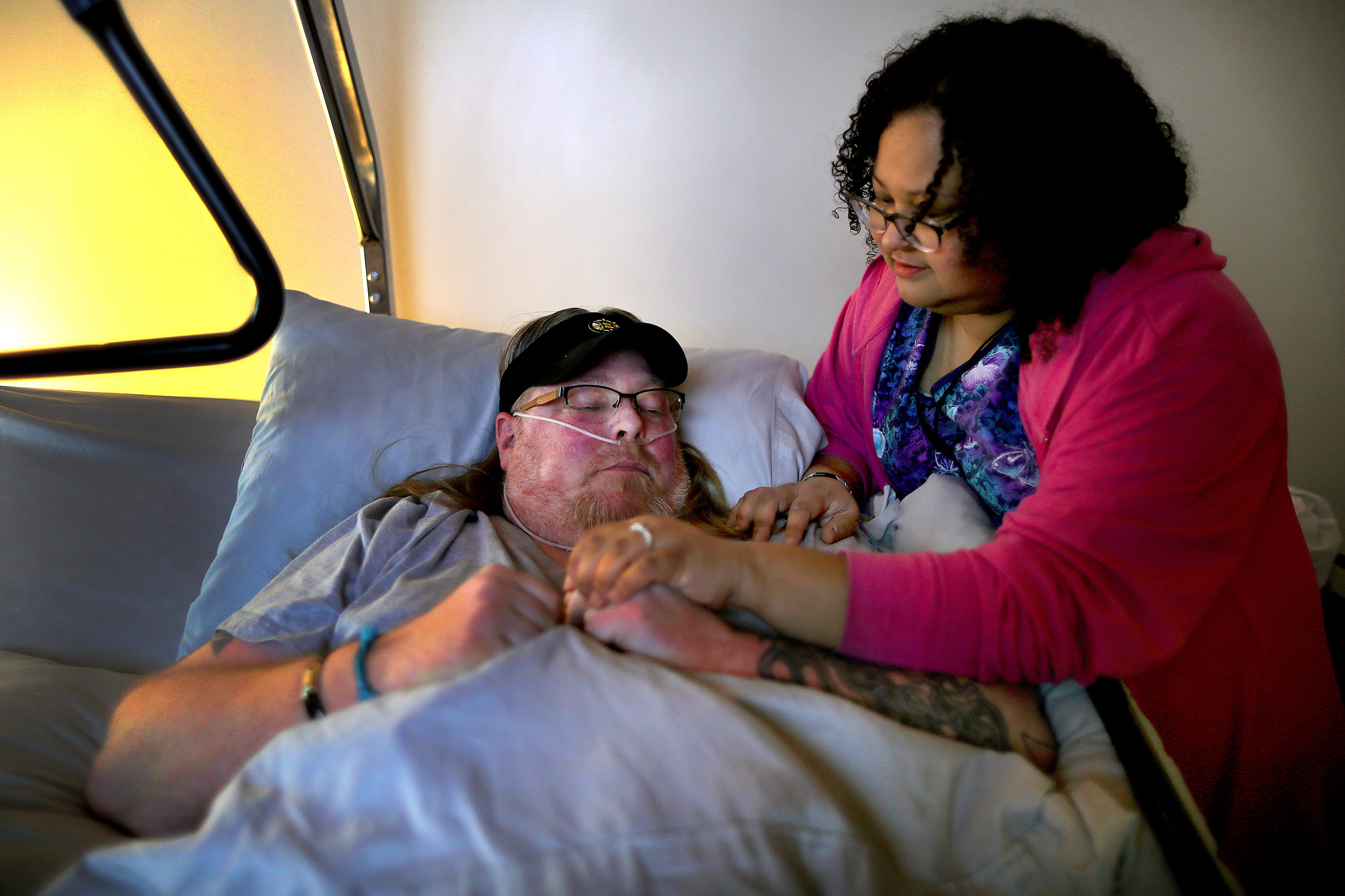 Melissa Baptista checks on her fiance Eric McGuire, who is bedridden with several medical conditions in Franklin.