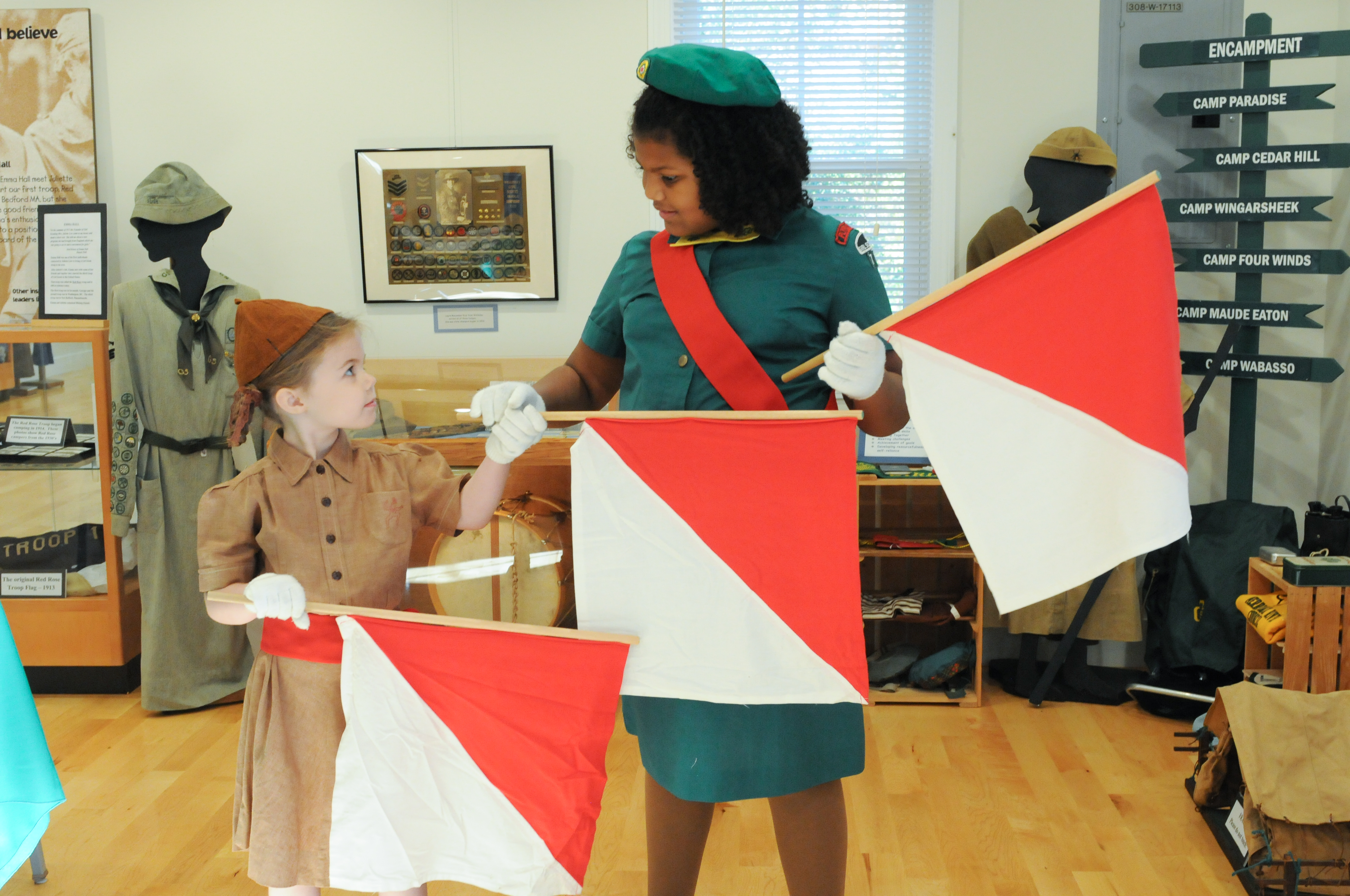 Two girl Scouts in vintage uniforms learn about the flag semaphore system.