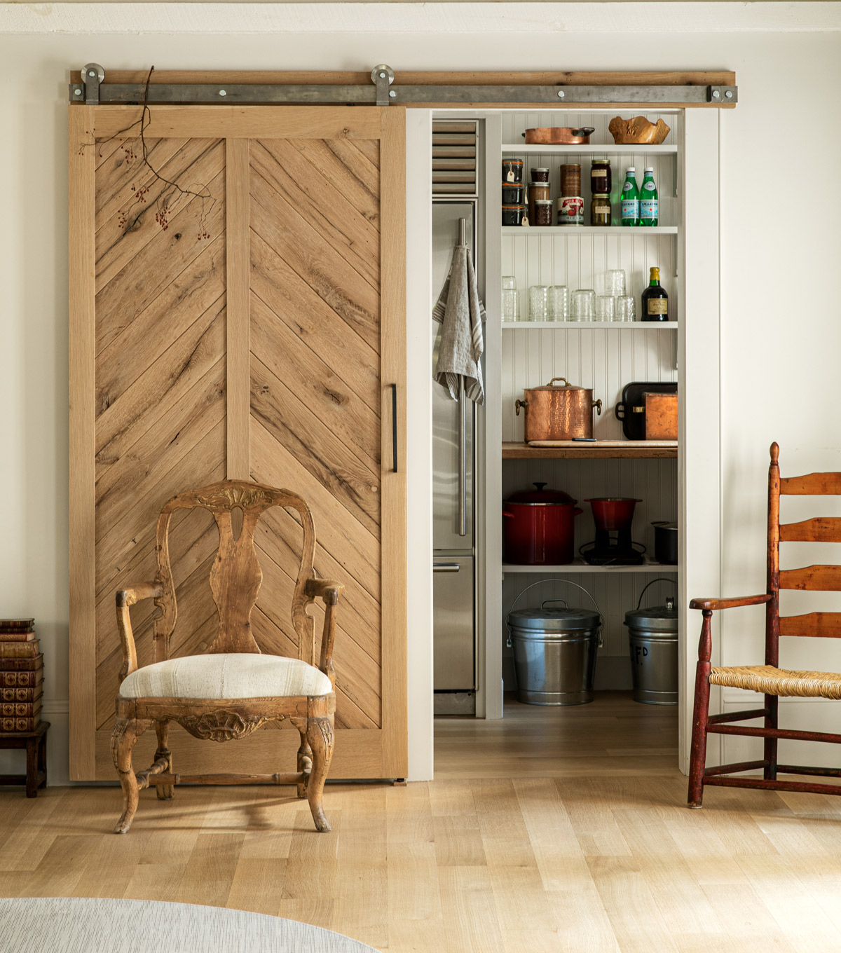 The pantry’s barn-style door is made from reclaimed white oak arranged in a chevron pattern. Gregory says, “Our old fridge fit in the pantry perfectly.”
