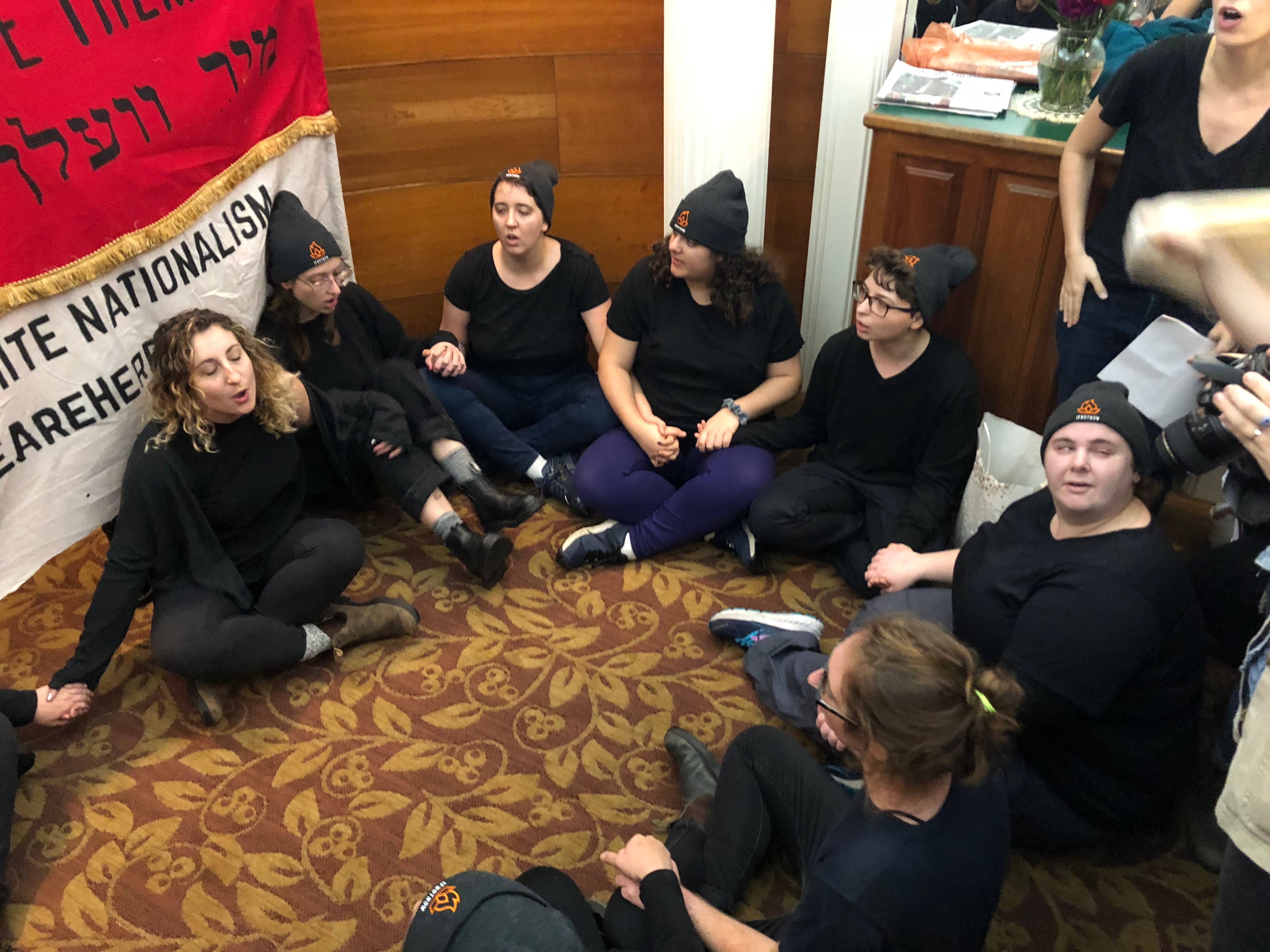 Protestors sit in a circle in the foyer of the Massachusetts GOP office downtown.
