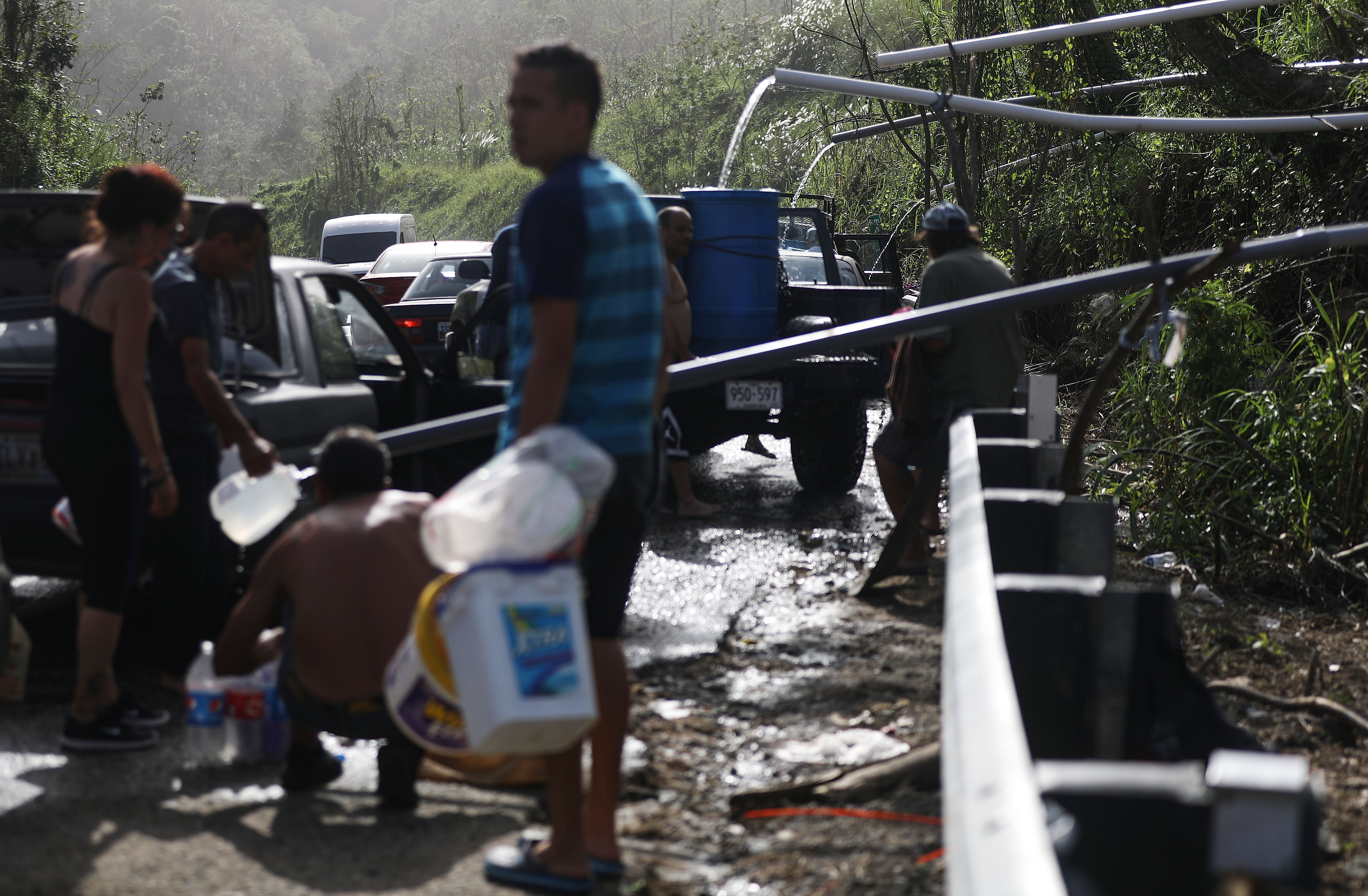 People fill containers with water funneled through pipes from a mountain stream on Oct. 19, nearly one month after Hurricane Maria struck, in Utuado, Puerto Rico.