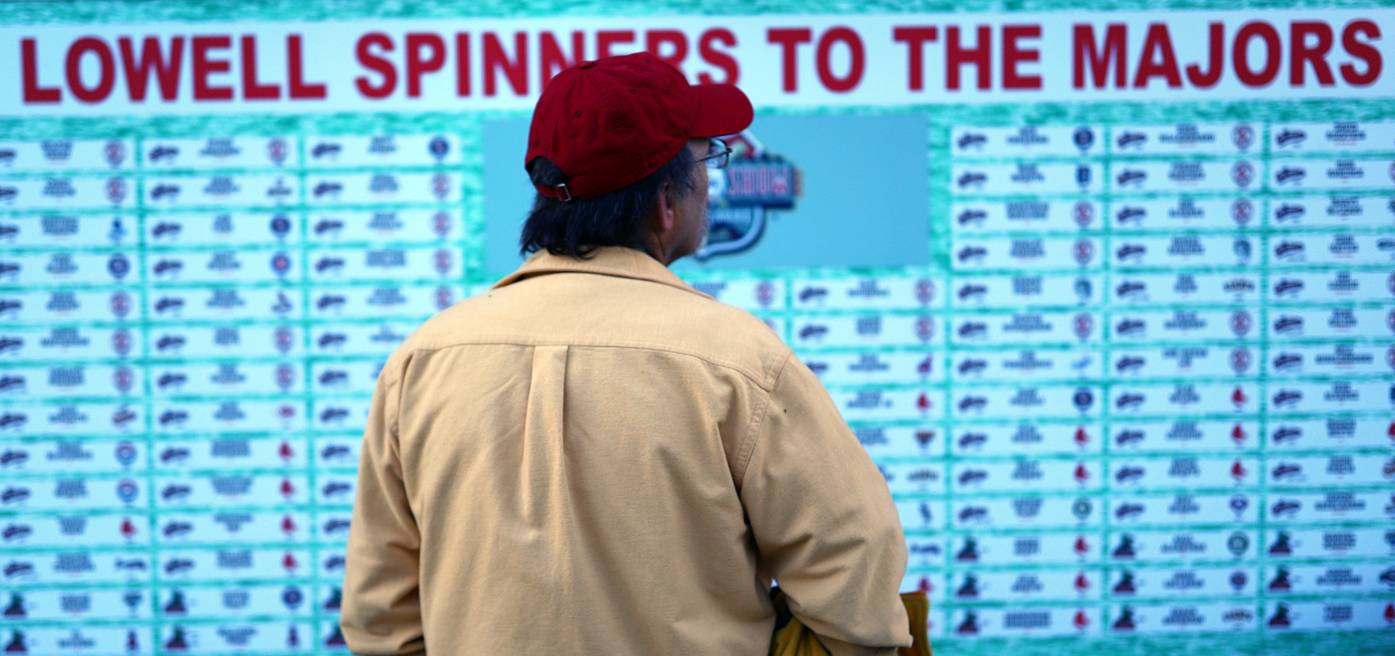 A fan reads the list of past Lowell Spinners players who have gone onto the majors, during the Spinners home opener.