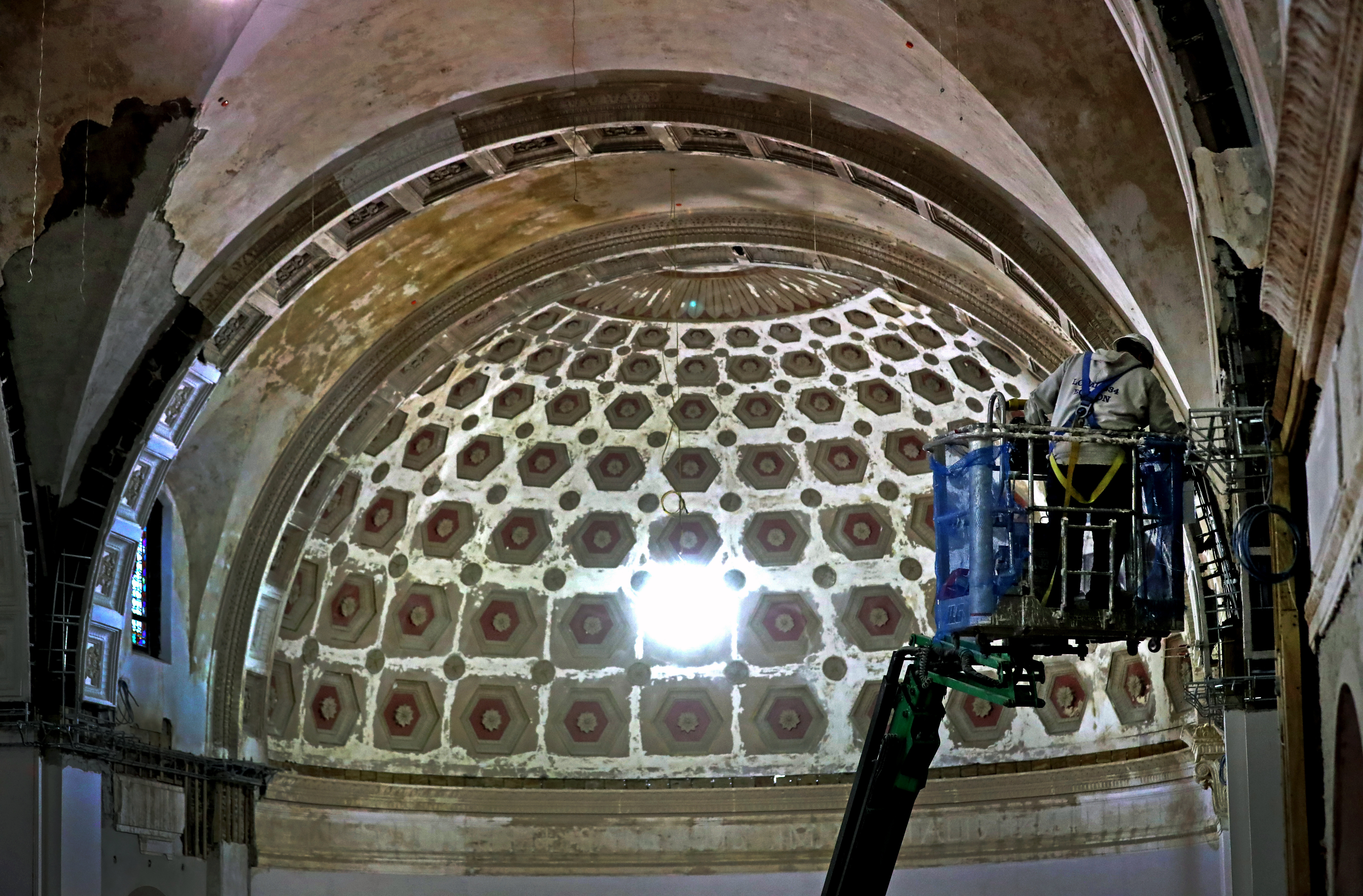 A construction worker on a lift works on the restoriation of the vaulted ceiling at St. Gabriel’s Church.