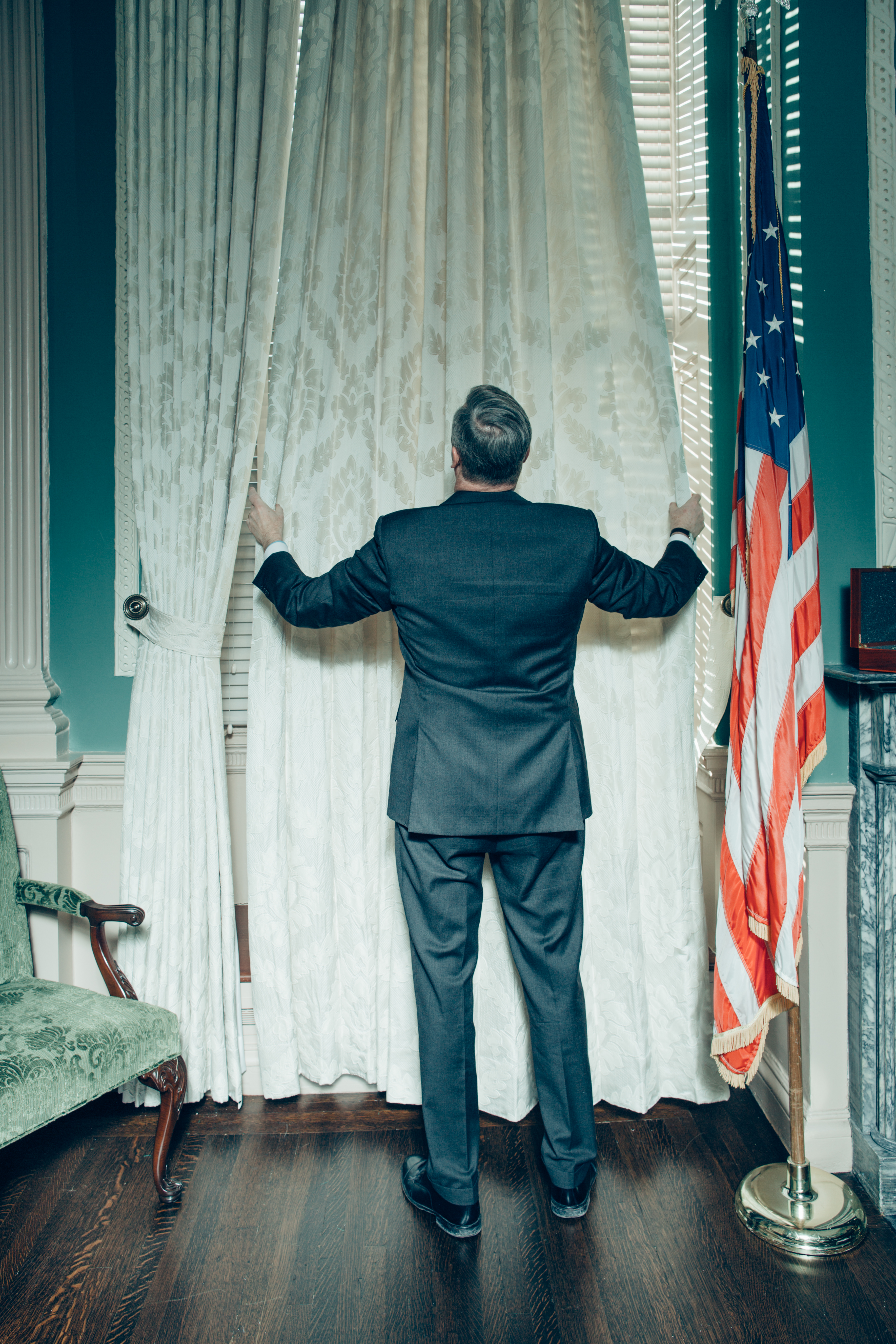 For lighting during a photo shoot, Charlie Baker adjusts the drapes his predecessor famously installed in the governor’s office.