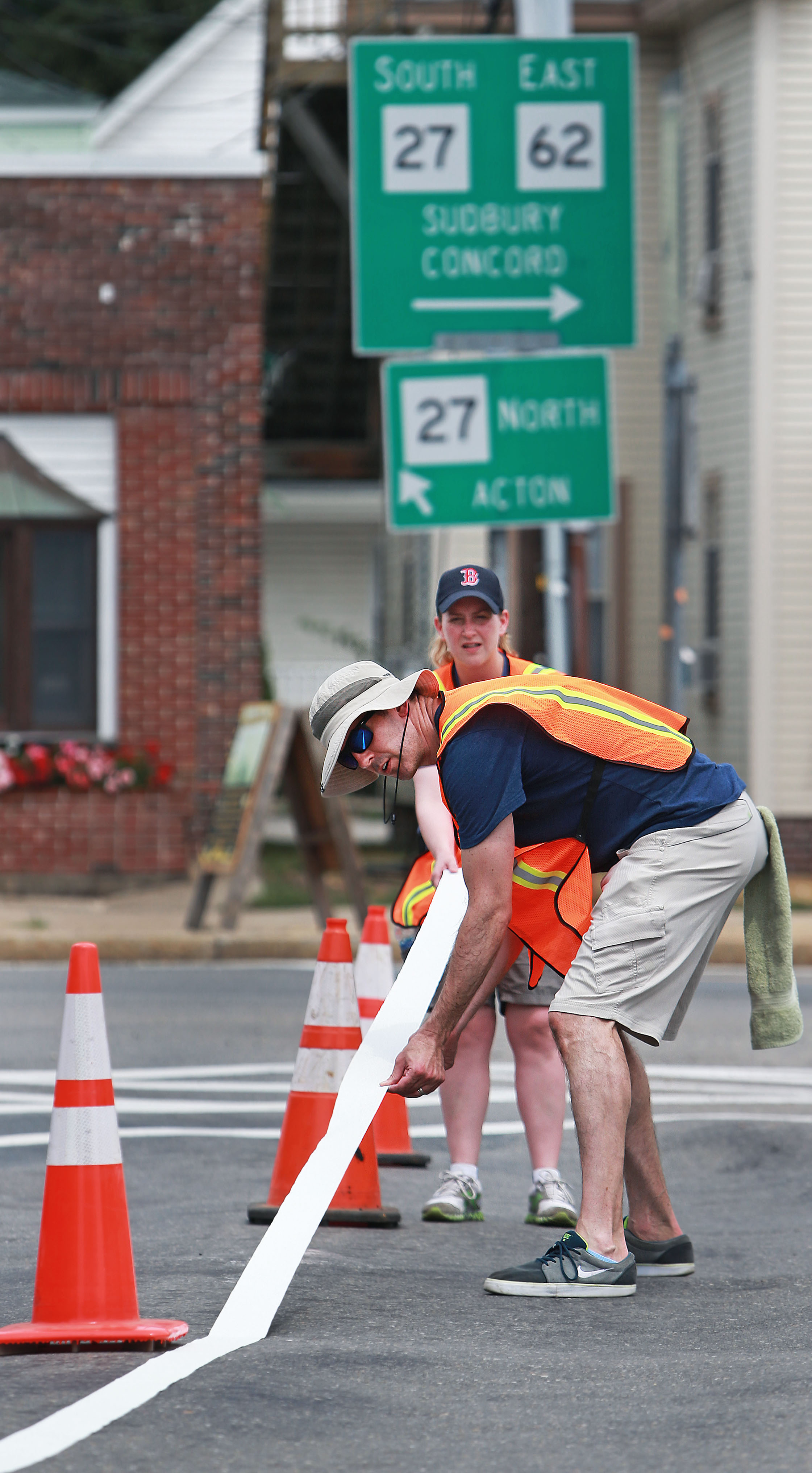 Barry Keppard (front) and Sarah Lee worked on laying down tape for a temporary bike lane in Maynard.