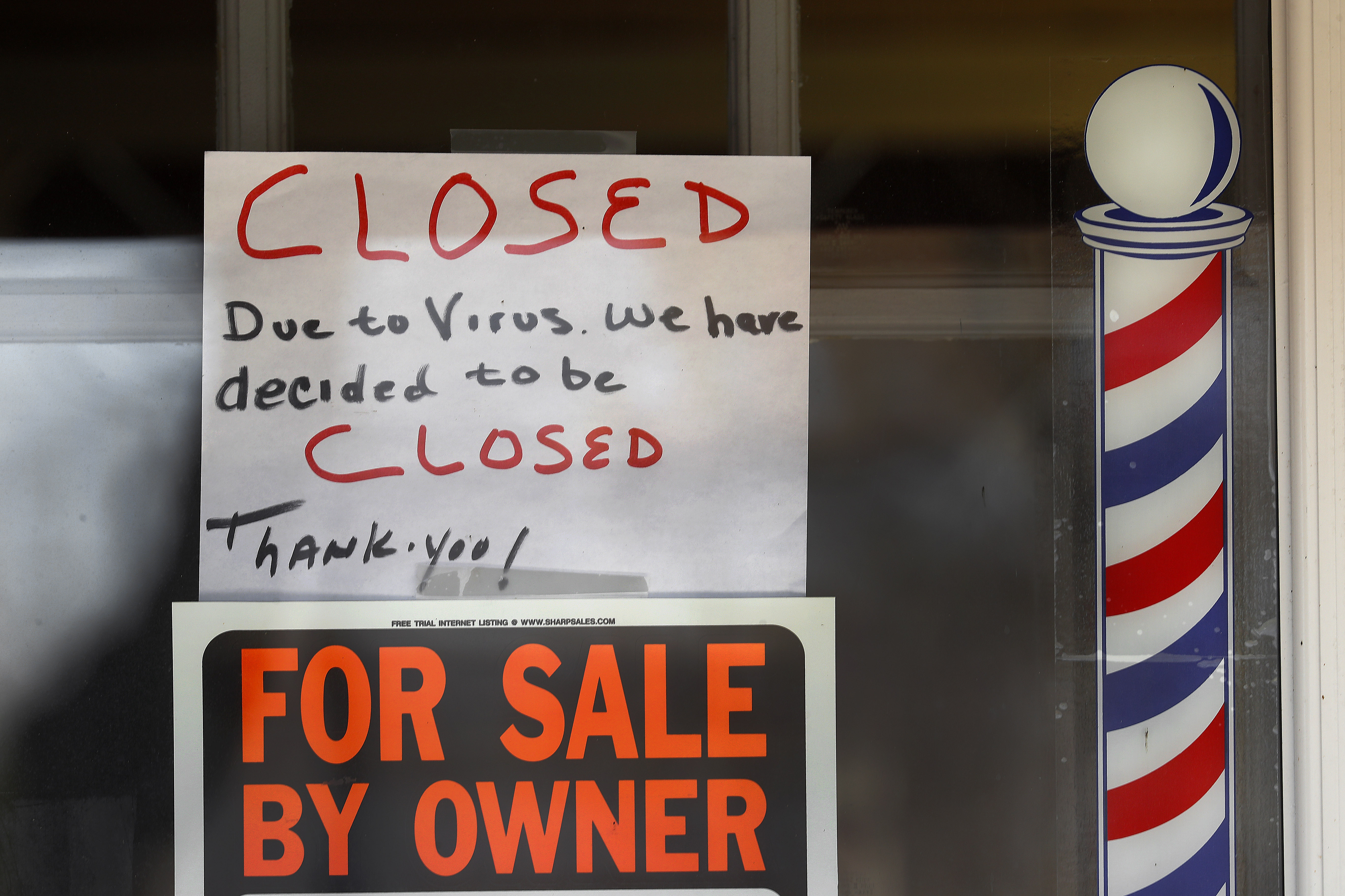 "For Sale By Owner" and "Closed Due to Virus" signs were displayed in the window of a business in Grosse Pointe Woods, Mich.