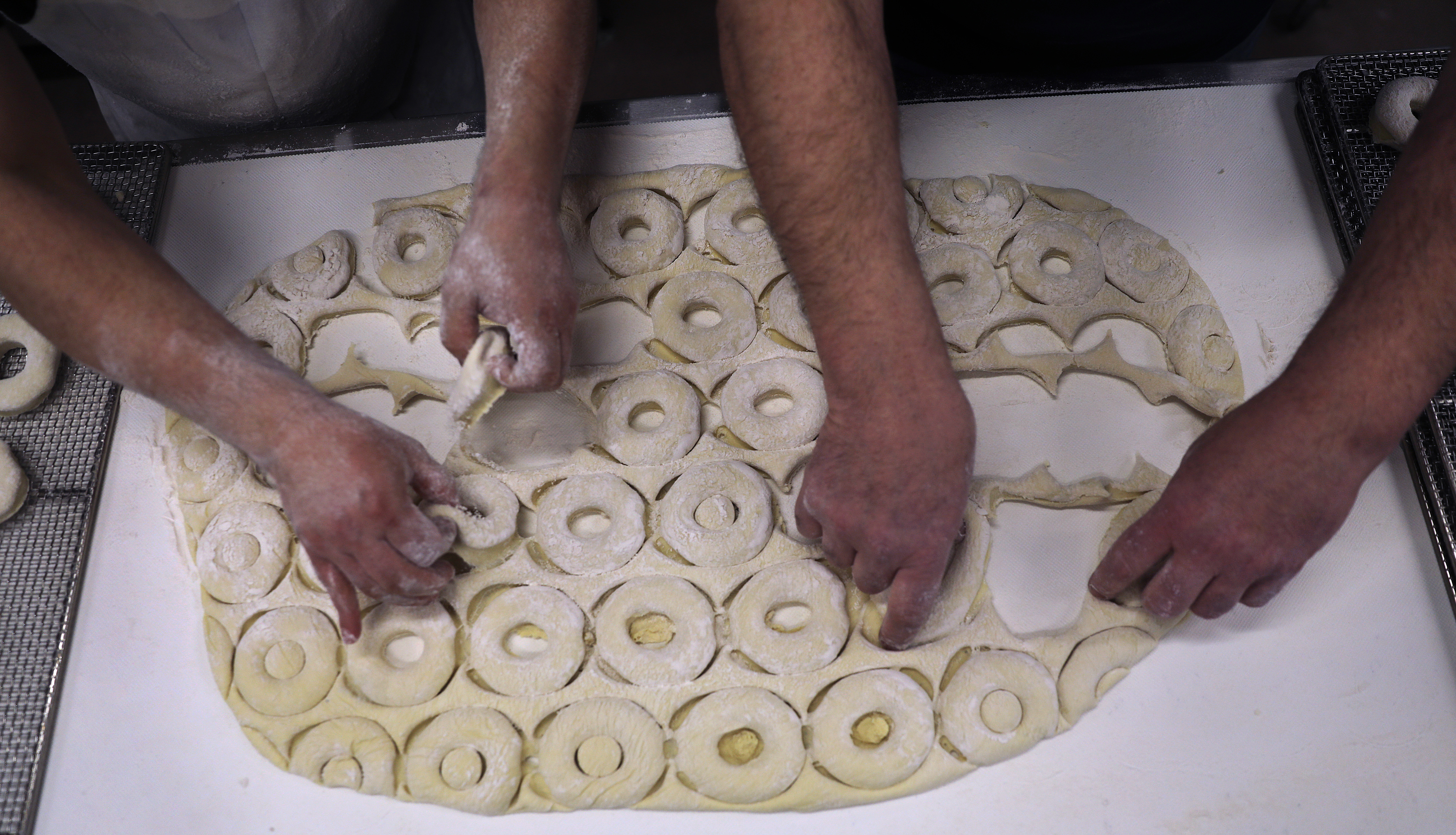 Head baker Rigoberto Cartagena, left, and co-owner and president Paul Delios separated the cut donuts from the dough.