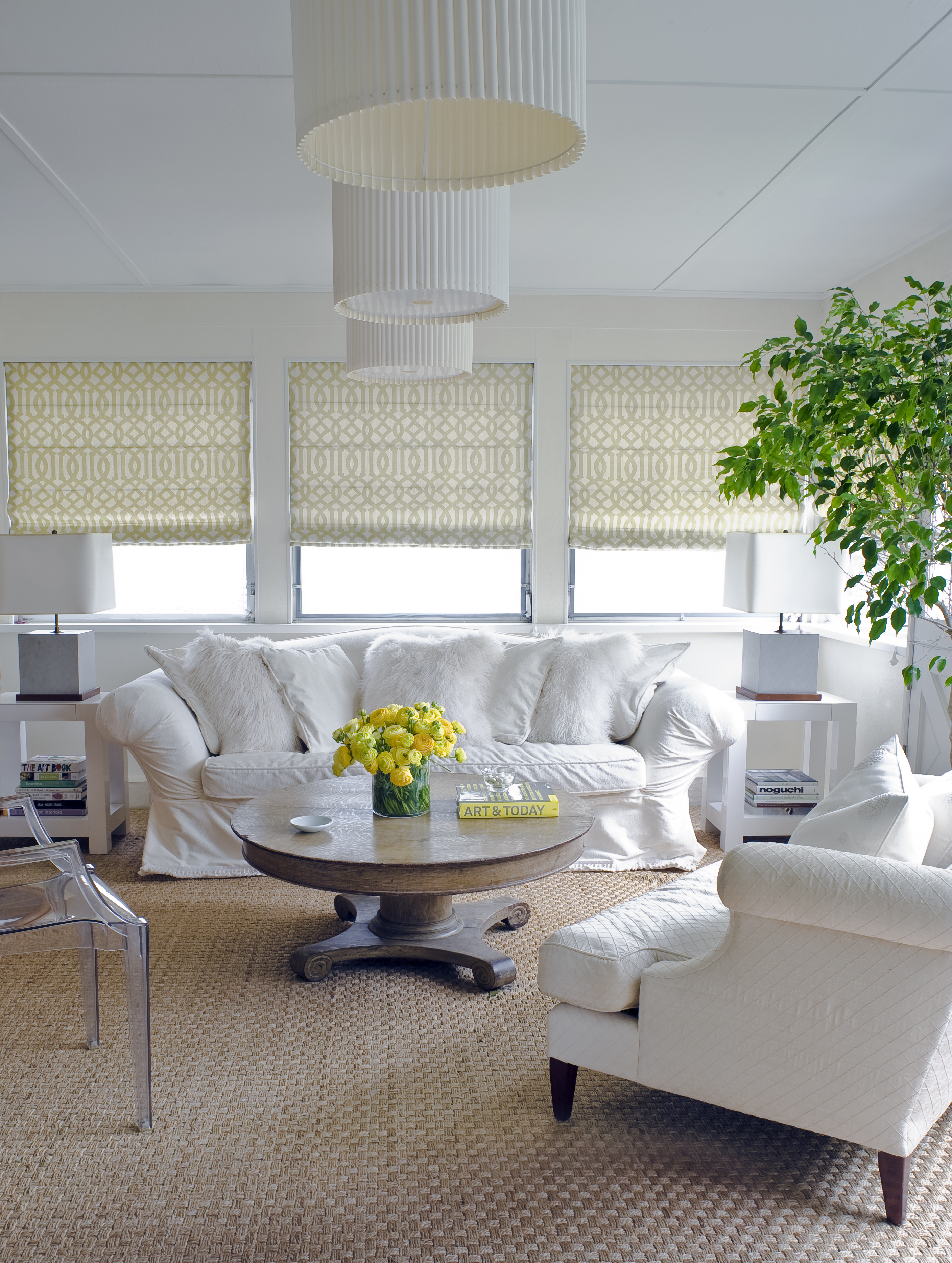 Dramatic touches of yellow bring warmth and energy to contrast with the crisp whites and soft, natural wood tones in this relaxing sunroom by New York-based interior designer Young Huh.