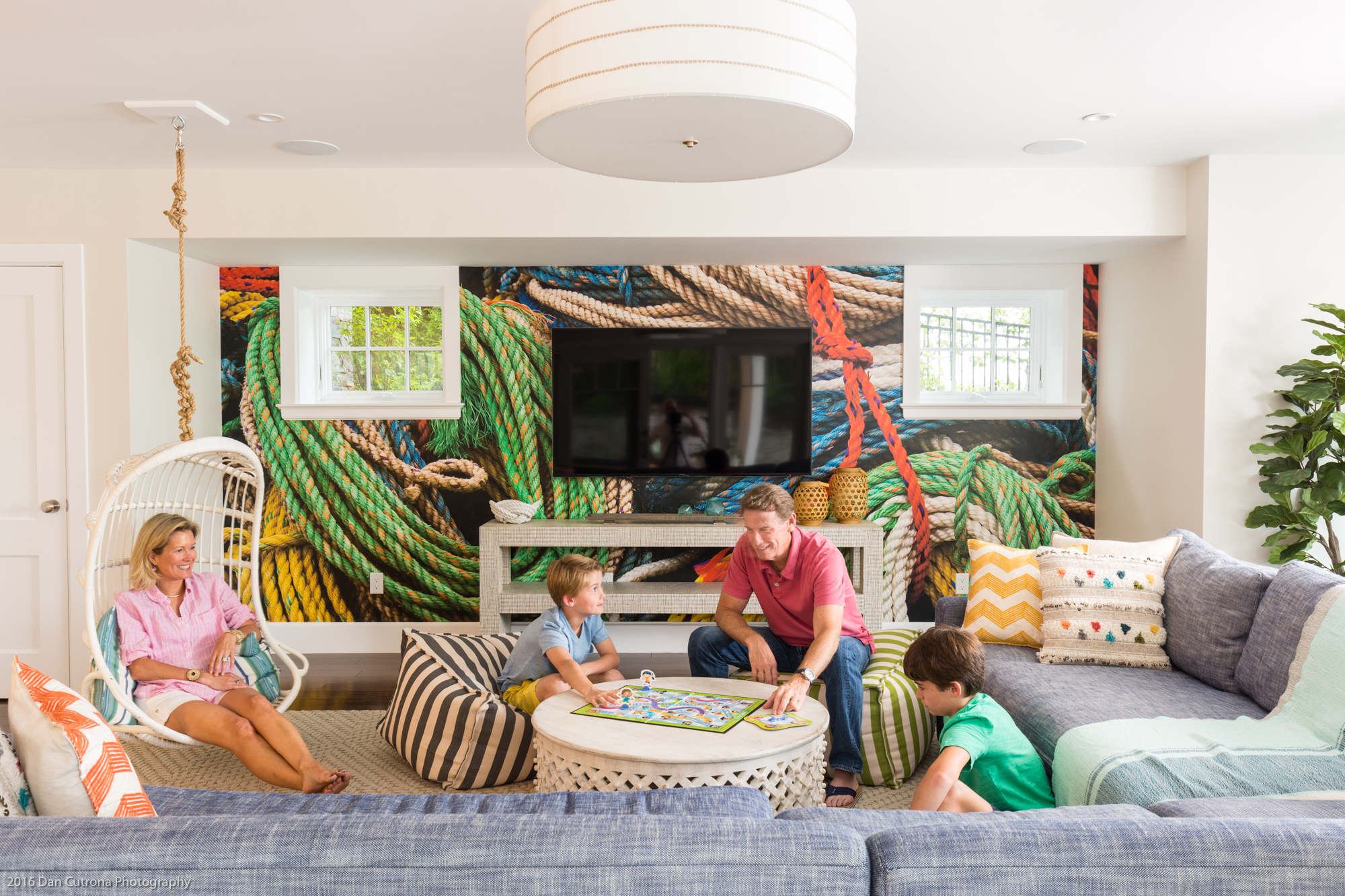 In the rec room, Heather Shanahan sits in a hanging rattan chair from Serena & Lily while Rob plays a board game with Bobby, 8, and Johnny, 10.