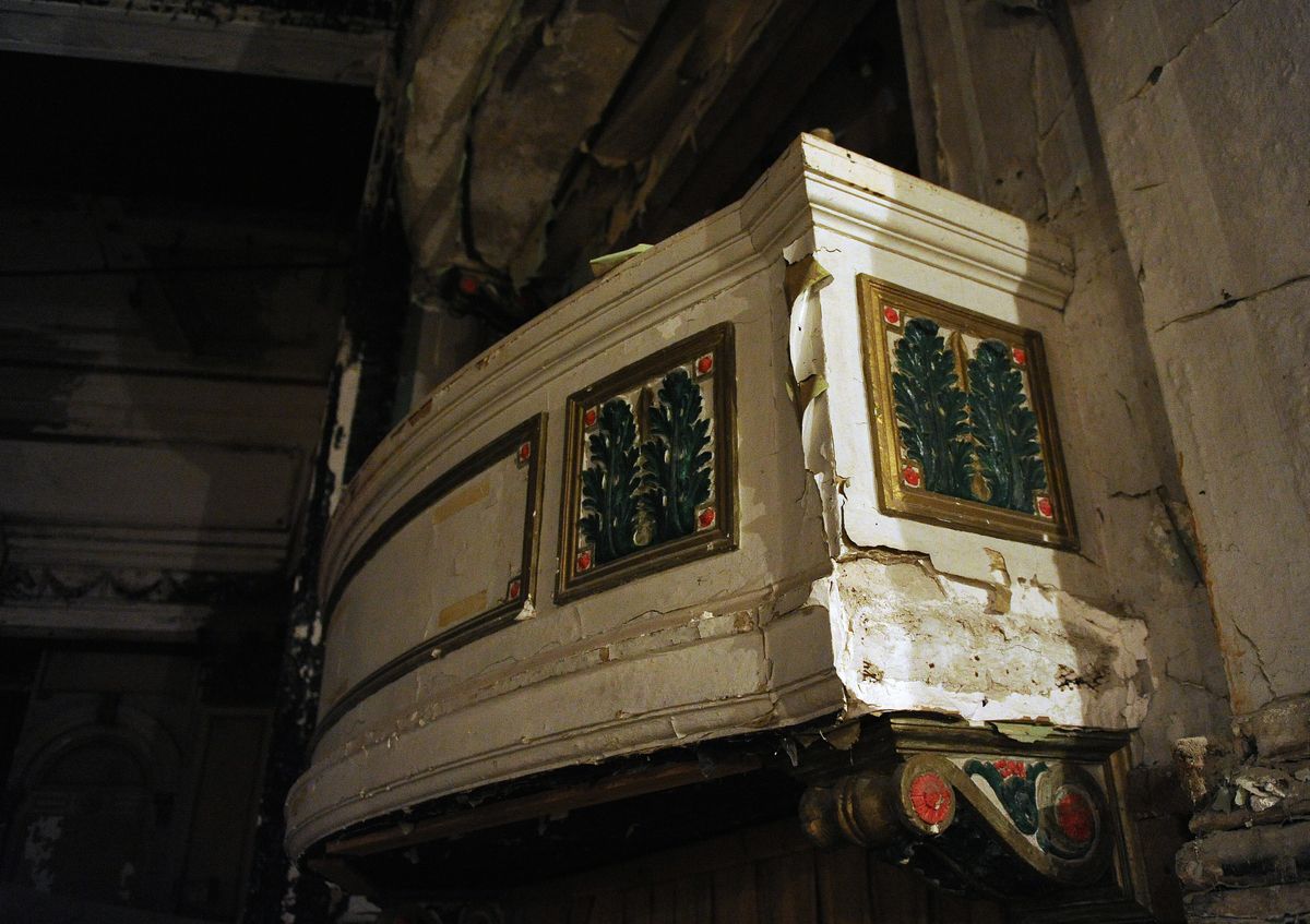 Much of the damage occurred long ago, when a roof leak caused the ceiling to collapse. Above, a surviving opera box.