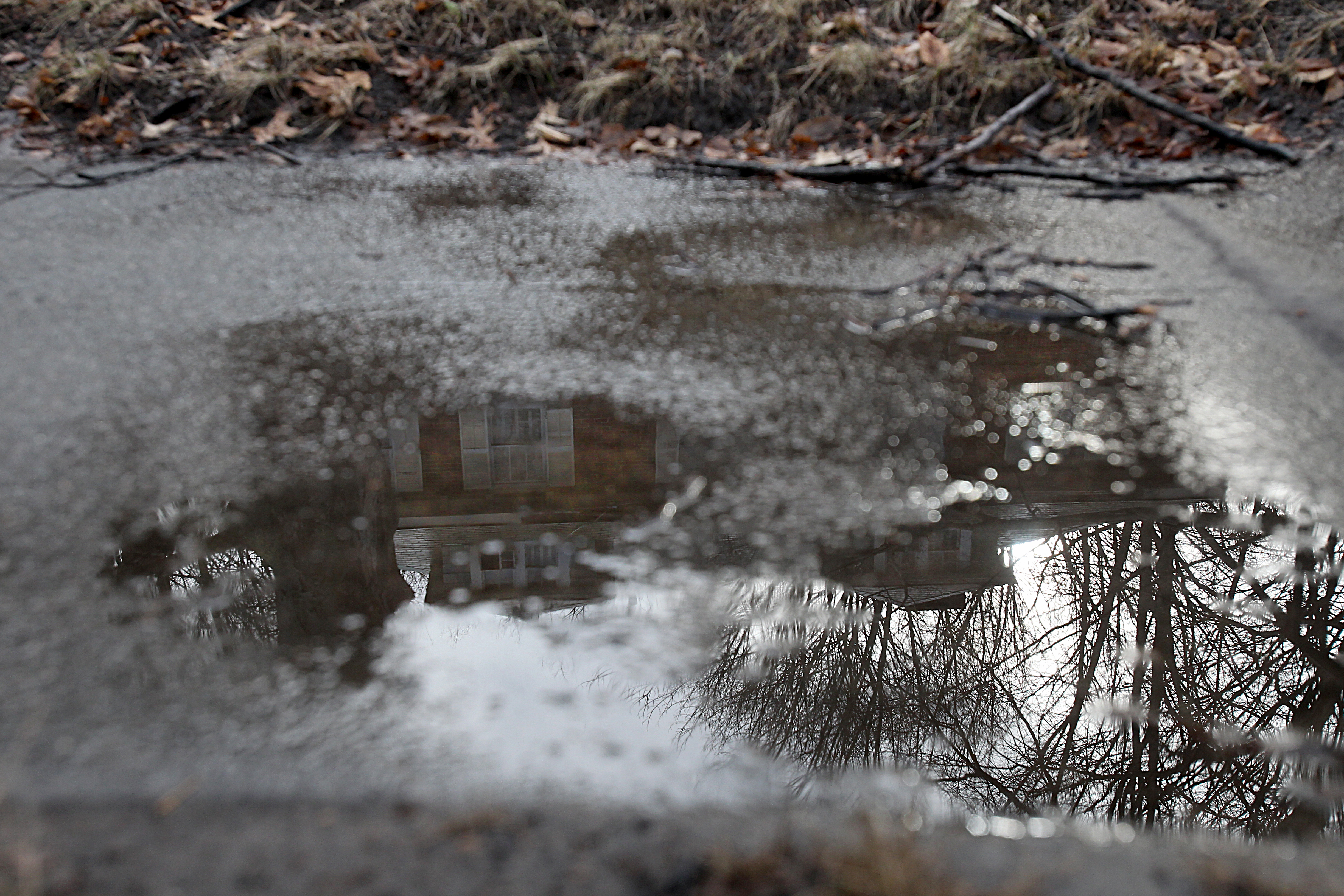 The Clinton Road home reflected in a puddle on the sidewalk.