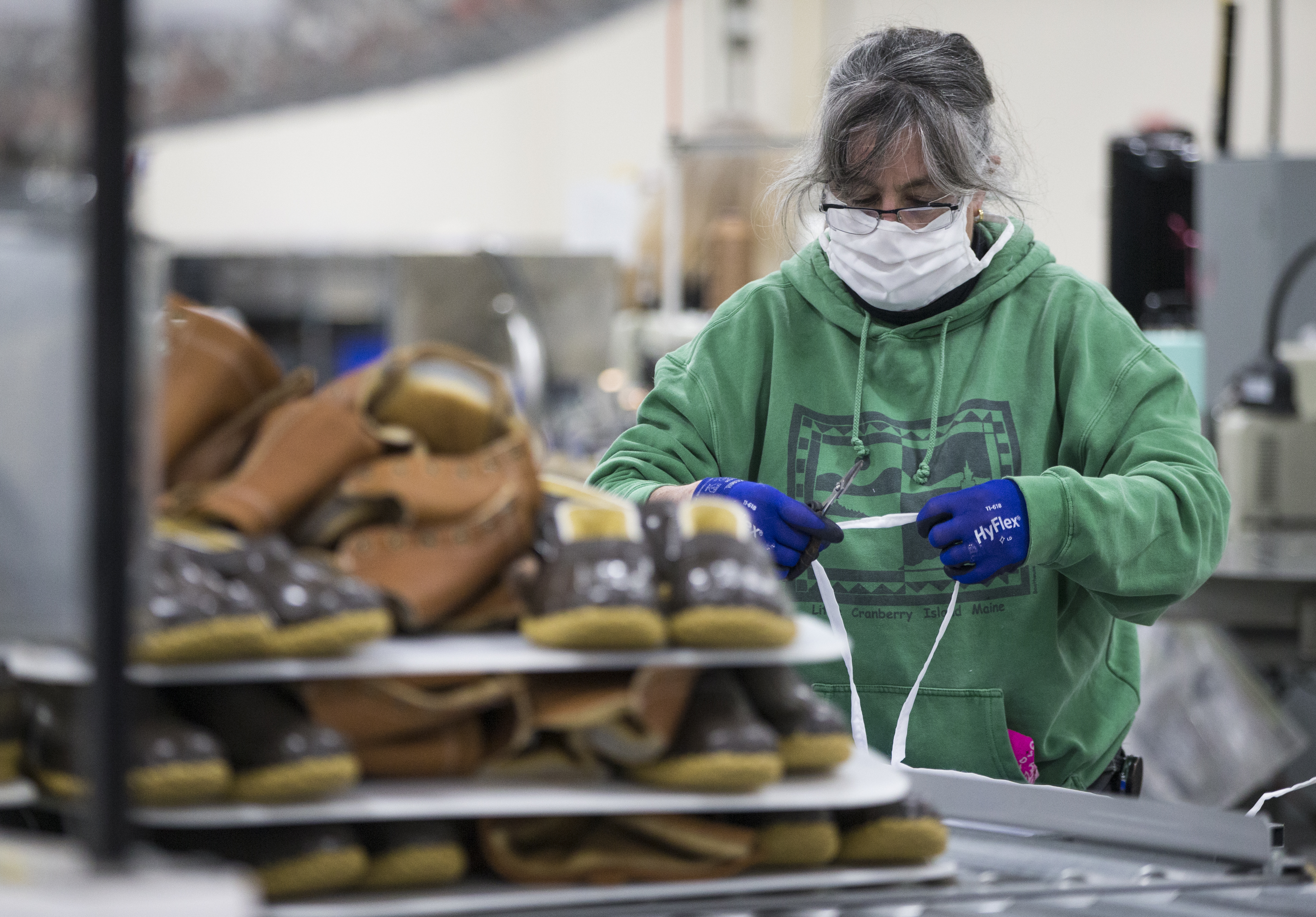 Tej Dickens measured out the ties on masks behind a pile of incomplete boots at the L.L. Bean plant.