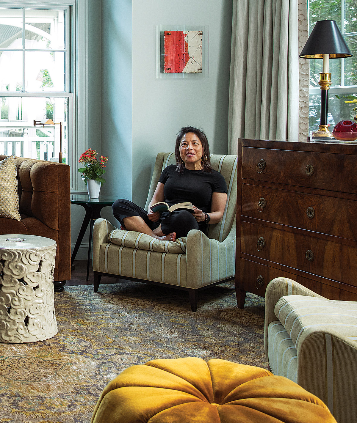 A mixed-media piece by Michelle Y. Williams from Jules Place hangs on the wall above Chu-Moyer, in a Sloop chair by Amy Somerville.
