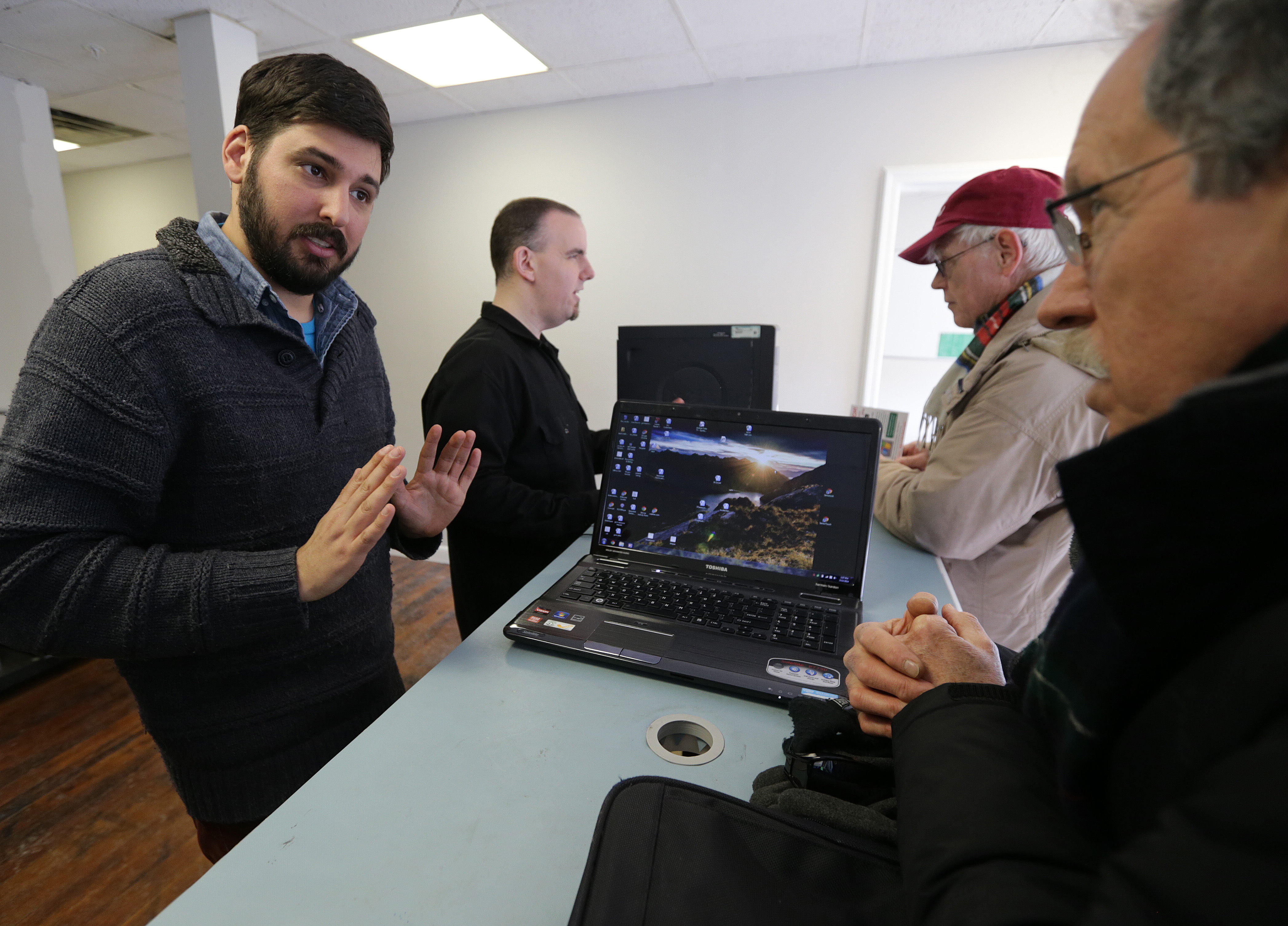 At Boston TechCollective in Somerville, (from left) Yochai Gal and Charlie Hoover assist customers Pat Hanlon and Brian Merrick with computer issues.