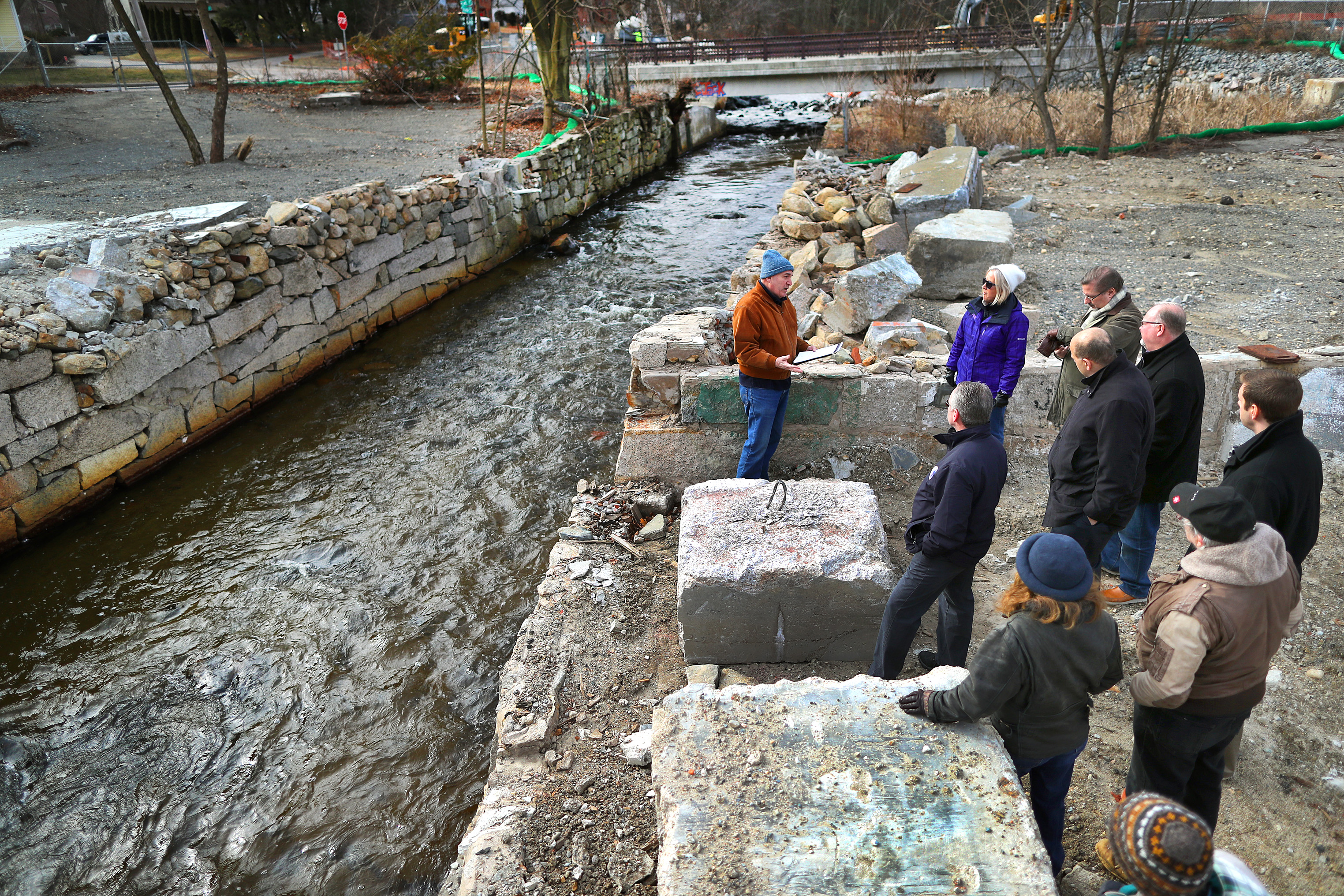 Alan Earls (left) took officials on a tour ot the Charles River Meadowlands. He stands at the site of a former mill that was torn down in Bellingham.