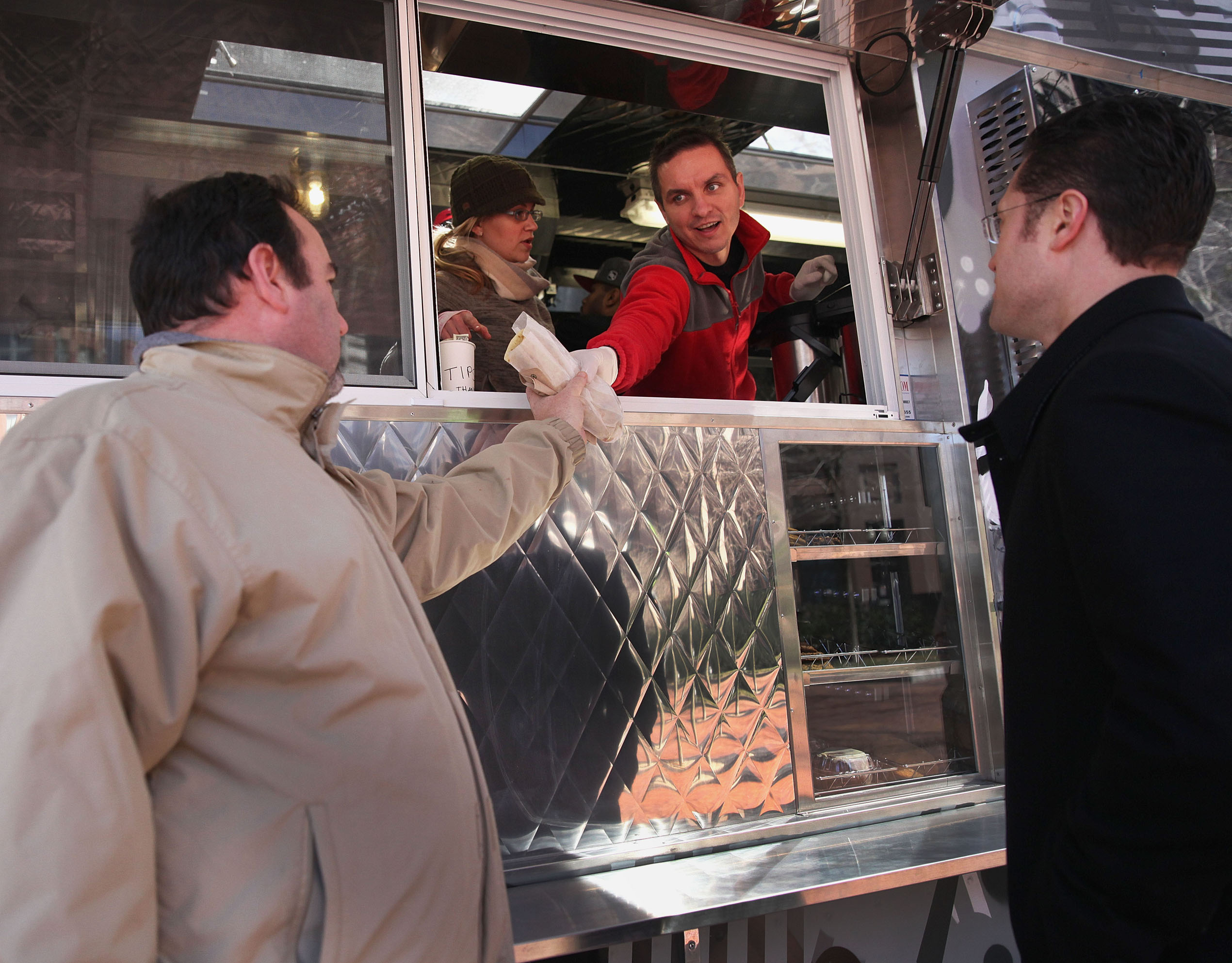 Raul Jurca handed out muffaletta piadini to customers Erik Killough (left) and Jamie McKenna.