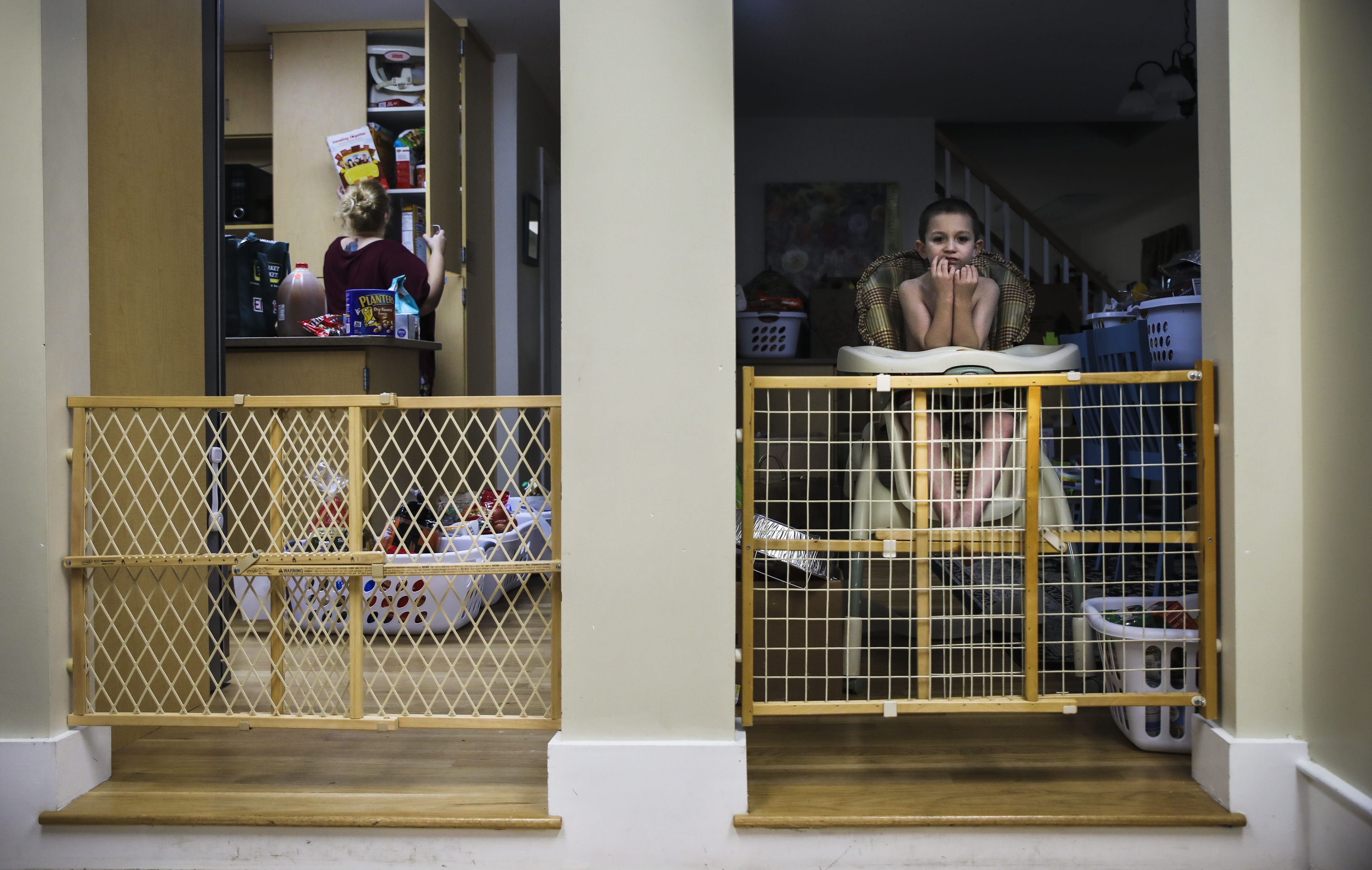 Mariah searched for after-school snacks at the Seacoast Family Promise day house in Exeter, N.H., while Dylan waited in a highchair. Mariah used the highchair to keep the 6-year-old focused and stationary while eating.