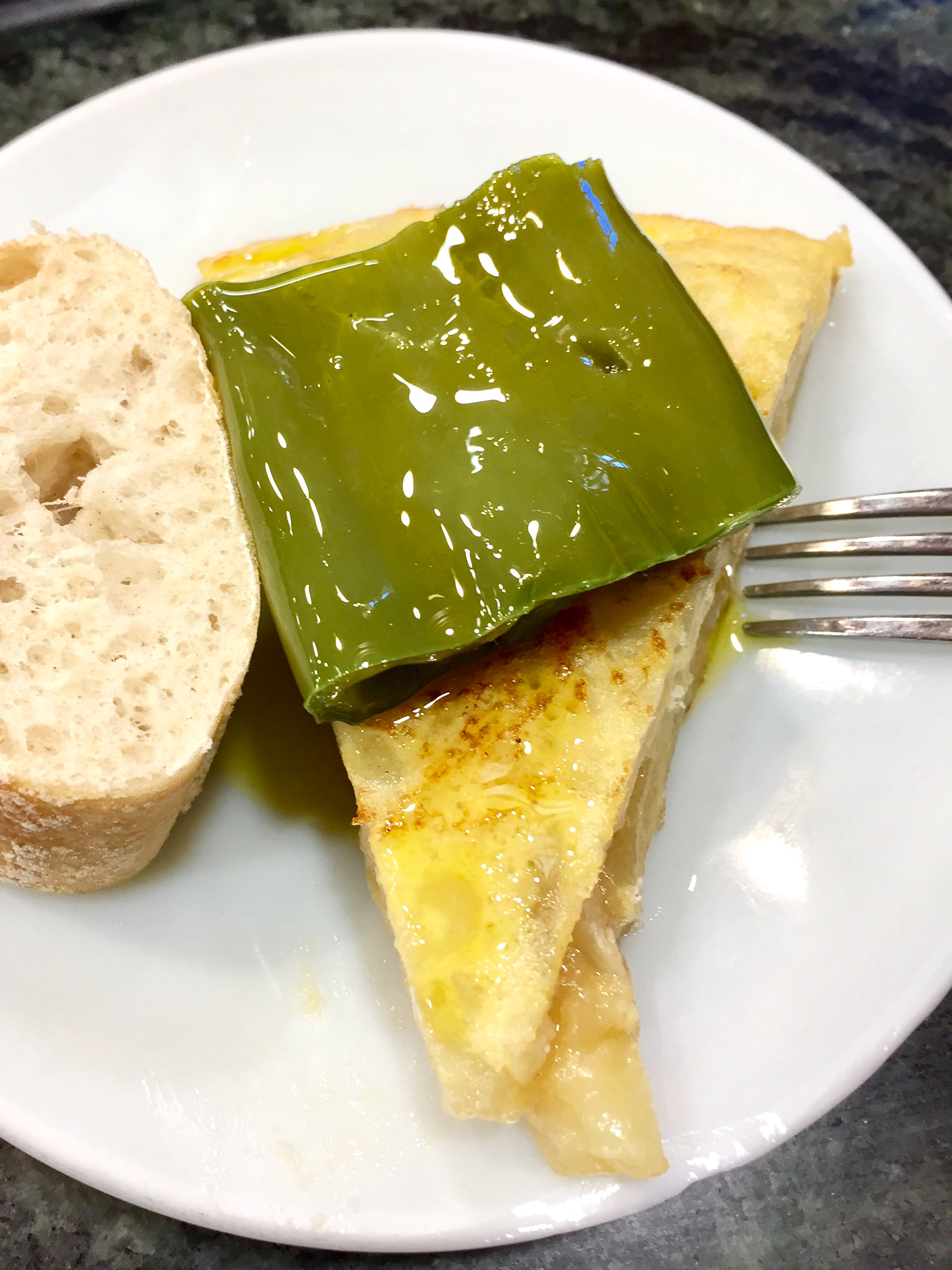 A wedge of traditional tortilla Española garnished with roasted green pepper.