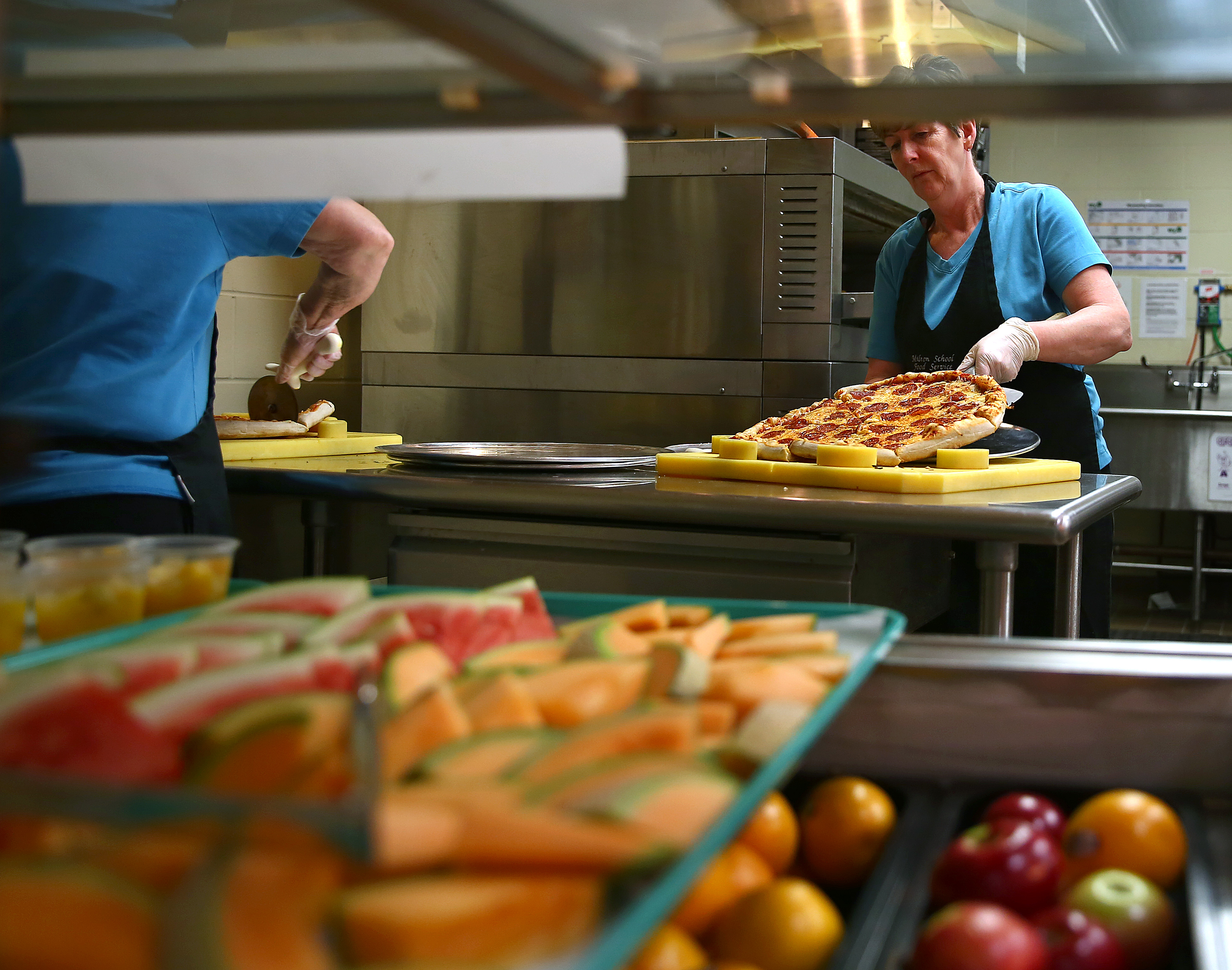 Barbara Doherty gets pizza ready to serve at Milton High School, where a variety of fresh fruit also is available.