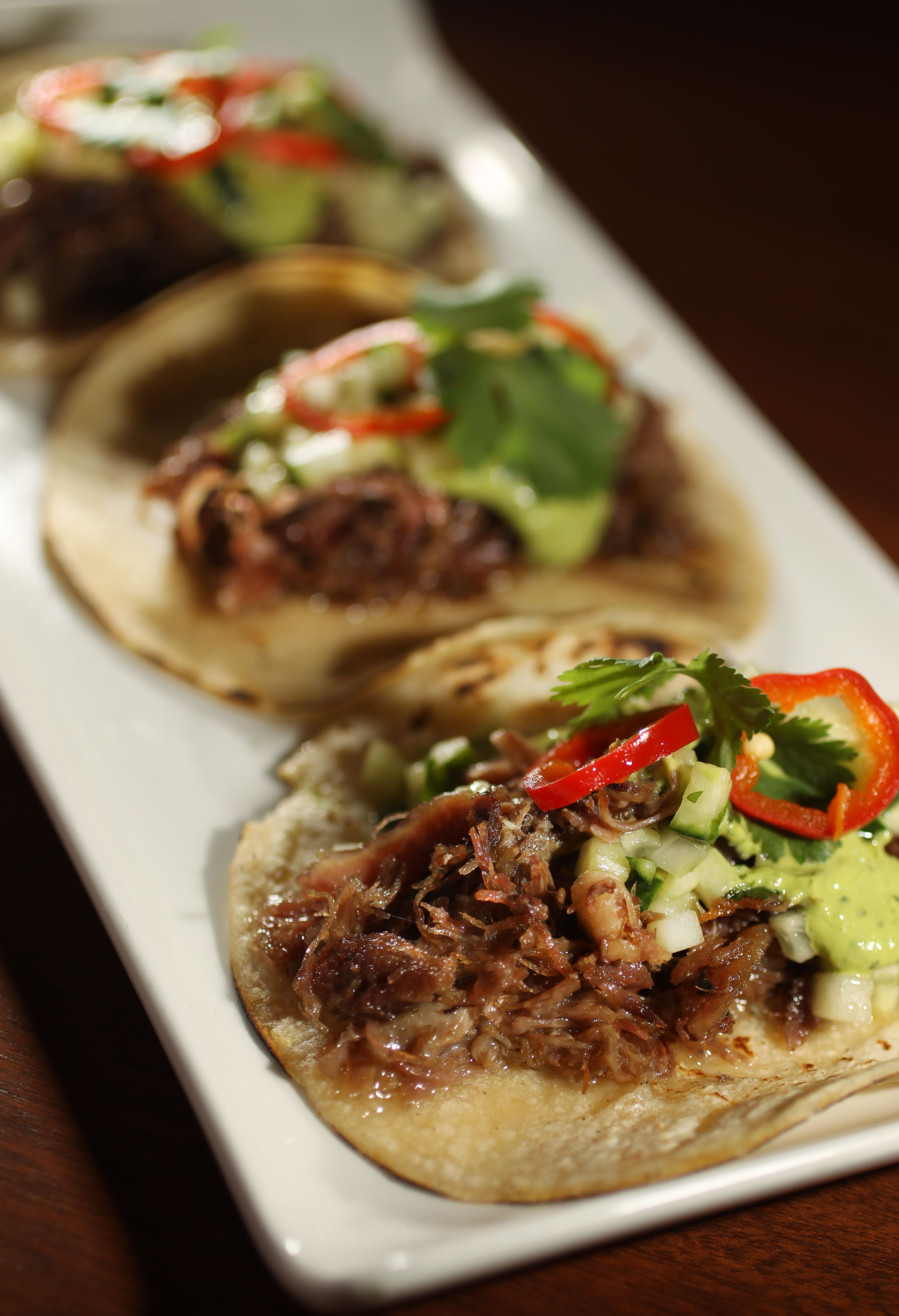 Tortillas topped with duck, cucumber, cilantro, mint, and chilies.