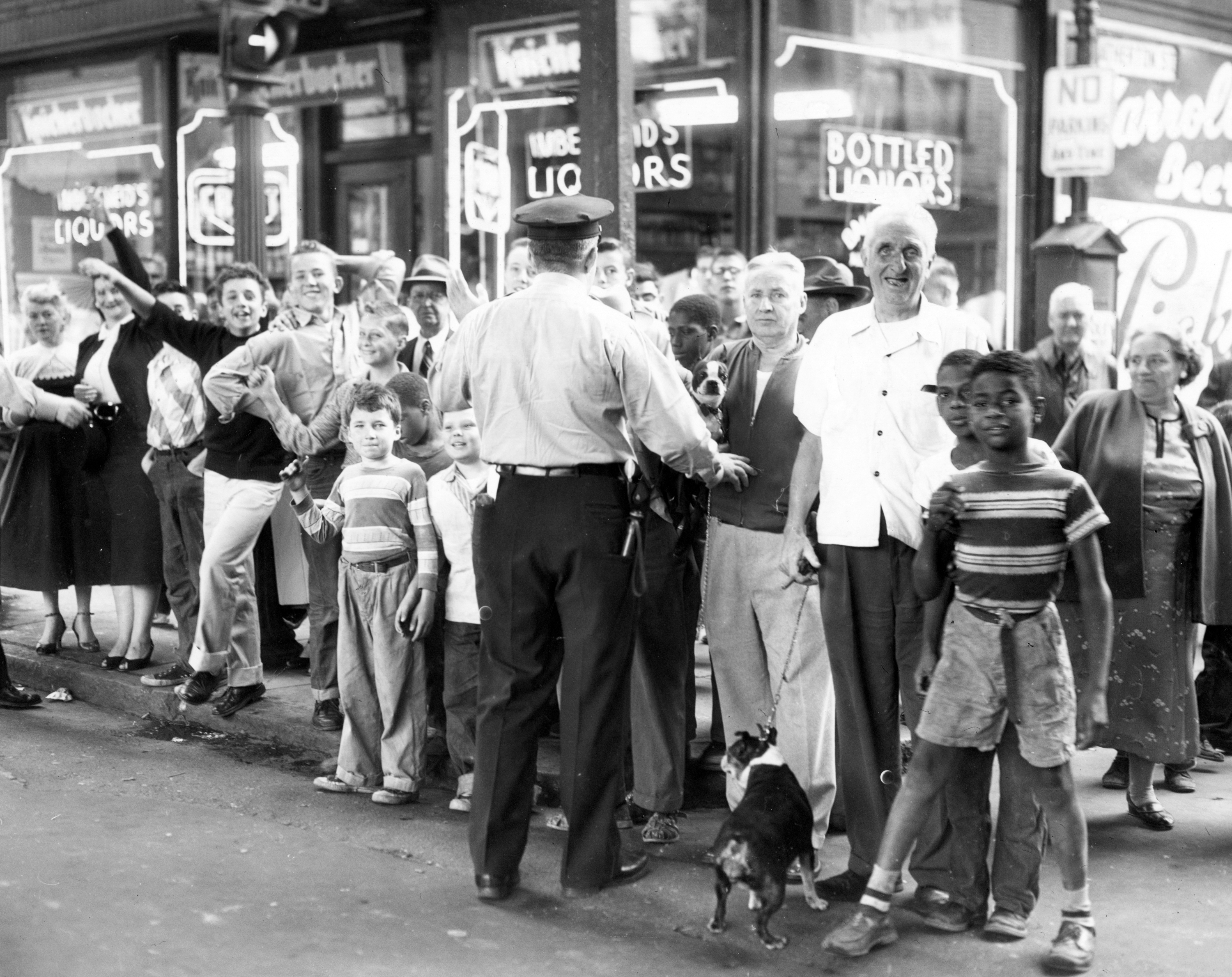 Police kept a crowd of spectators at bay as the all-male jury in the Brink's Inc. robbery trial toured Egleston Square, a location which figured in the prosecution's case. The one-day jury tour, held Aug. 30, 1956, was a traffic-stopper everywhere it went, as it was accompanied by a press corps of 100 reporters and photographers.