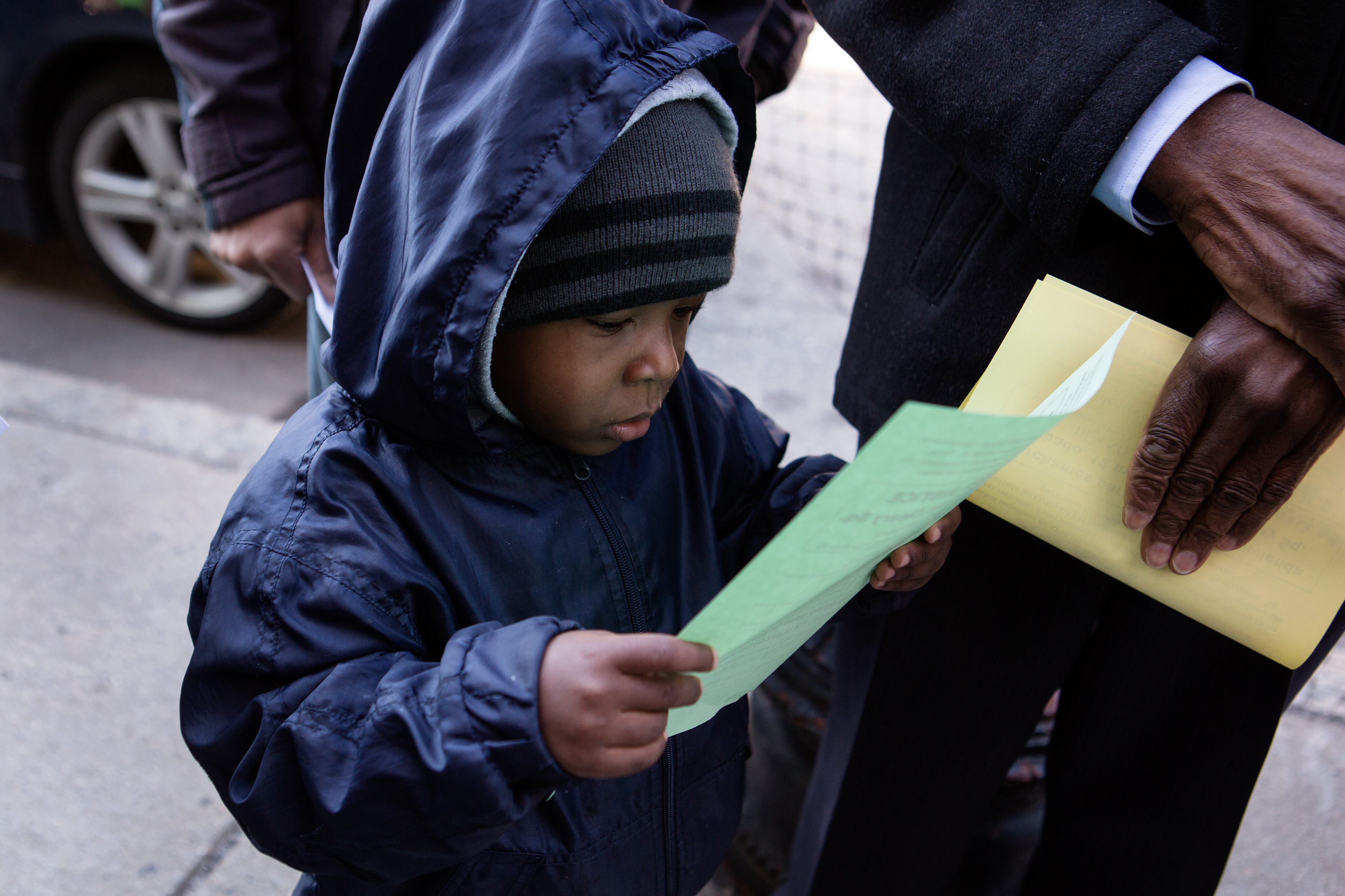 Telis Sebastian, 3, read a leaflet at the rally. He and his grandmother, Mary Pierre, live together and are facing displacement because of an unexpected increase in rent of $400.