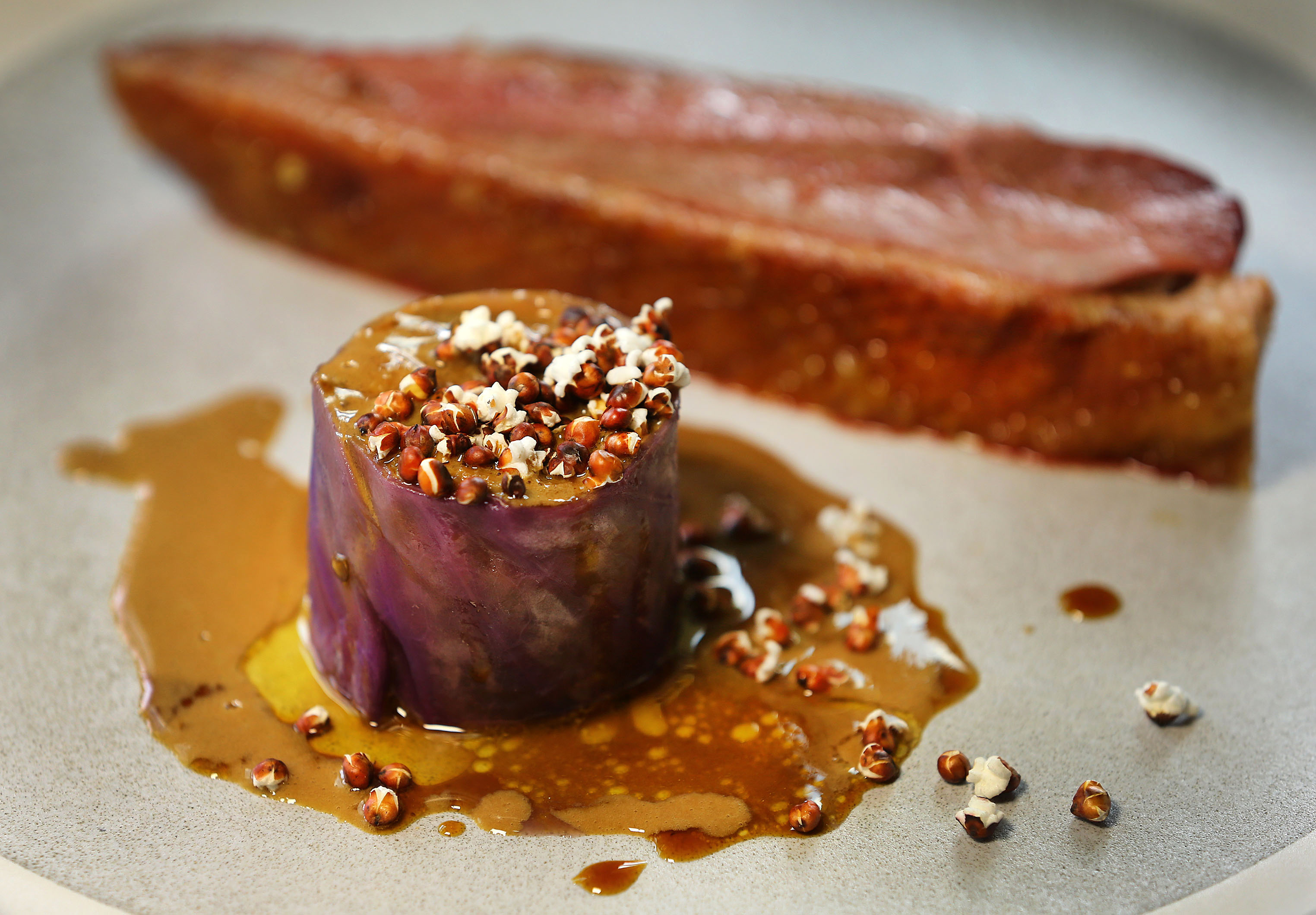 “That Duck in the Salt Marsh I Told You About,” a starkly plated apostrophe of dry-aged duck — skin crisped, bacon-esque — alongside cabbage-wrapped sardine and rice, sprinkled with popped sorghum and drizzled in liver sauce.