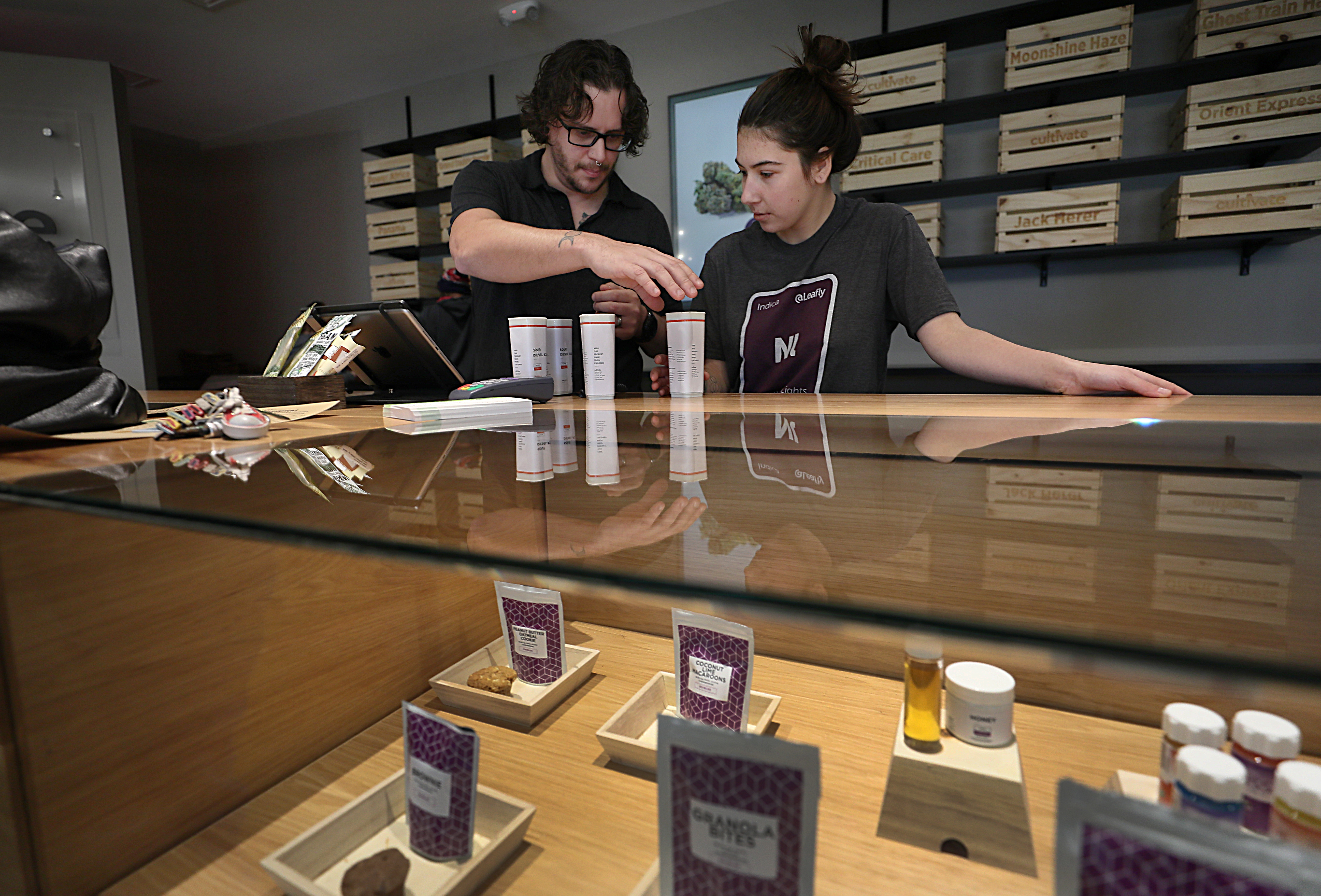 Employees, Nick Jarrin, left, and Kaylee Castell check out a customer buying medical marijuana at Cultivate.