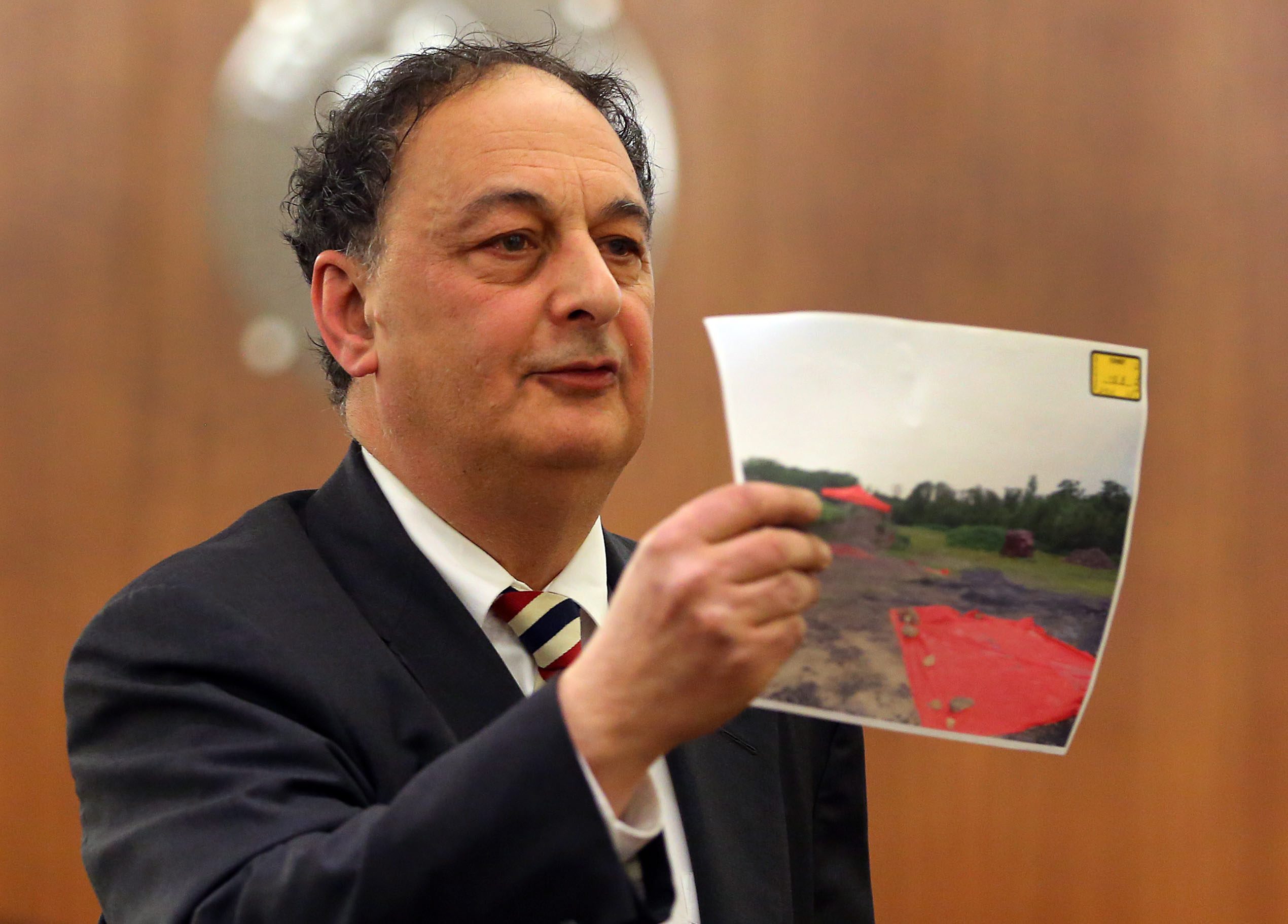 Defense attorney James Sultan holds a photo of the murder scene during closing arguments.