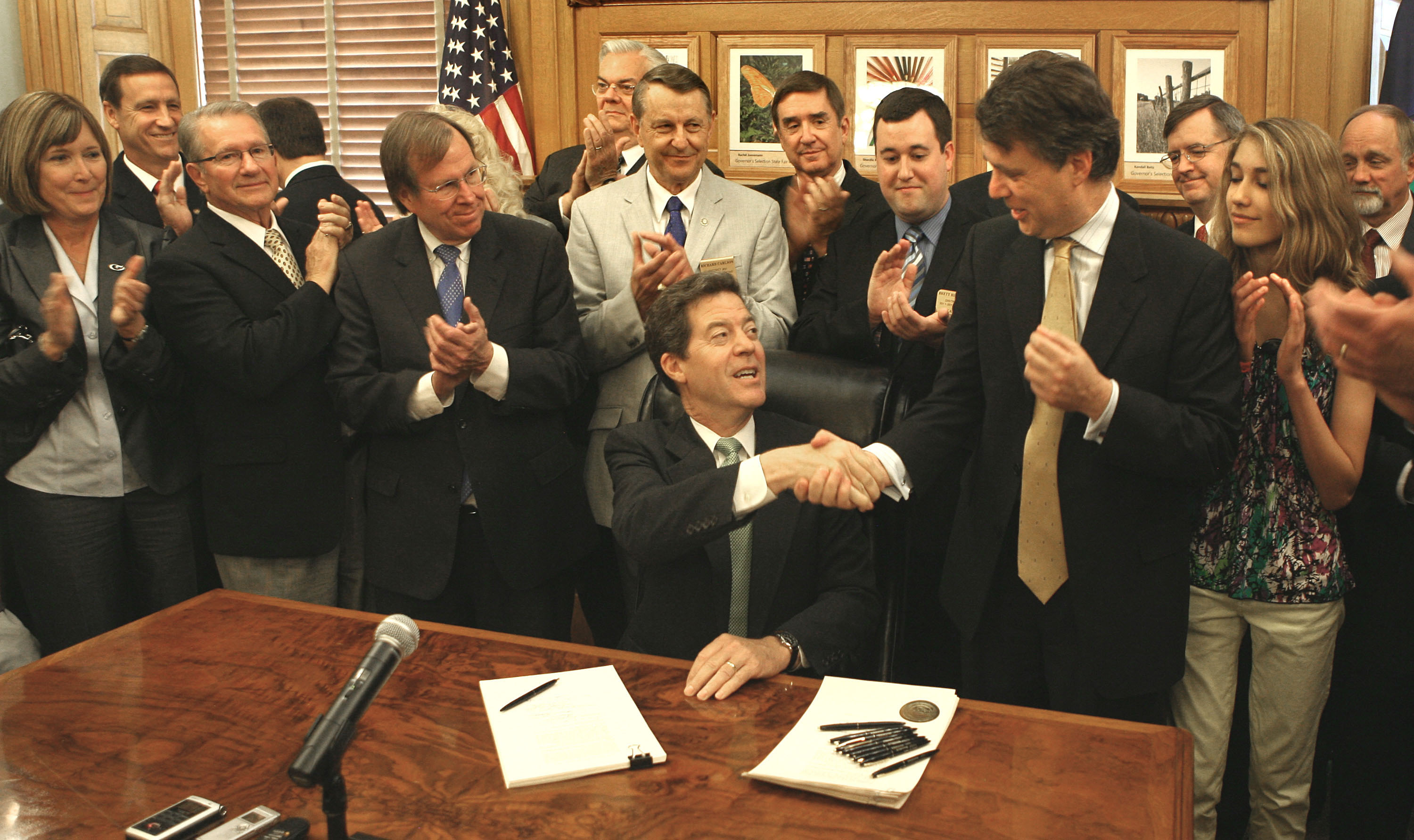 Governor Sam Brownback of Kansas (seated) in 2012 signed into law one of the largest tax cut bills in Kansas history, saying it would create “tens of thousands of new jobs.”