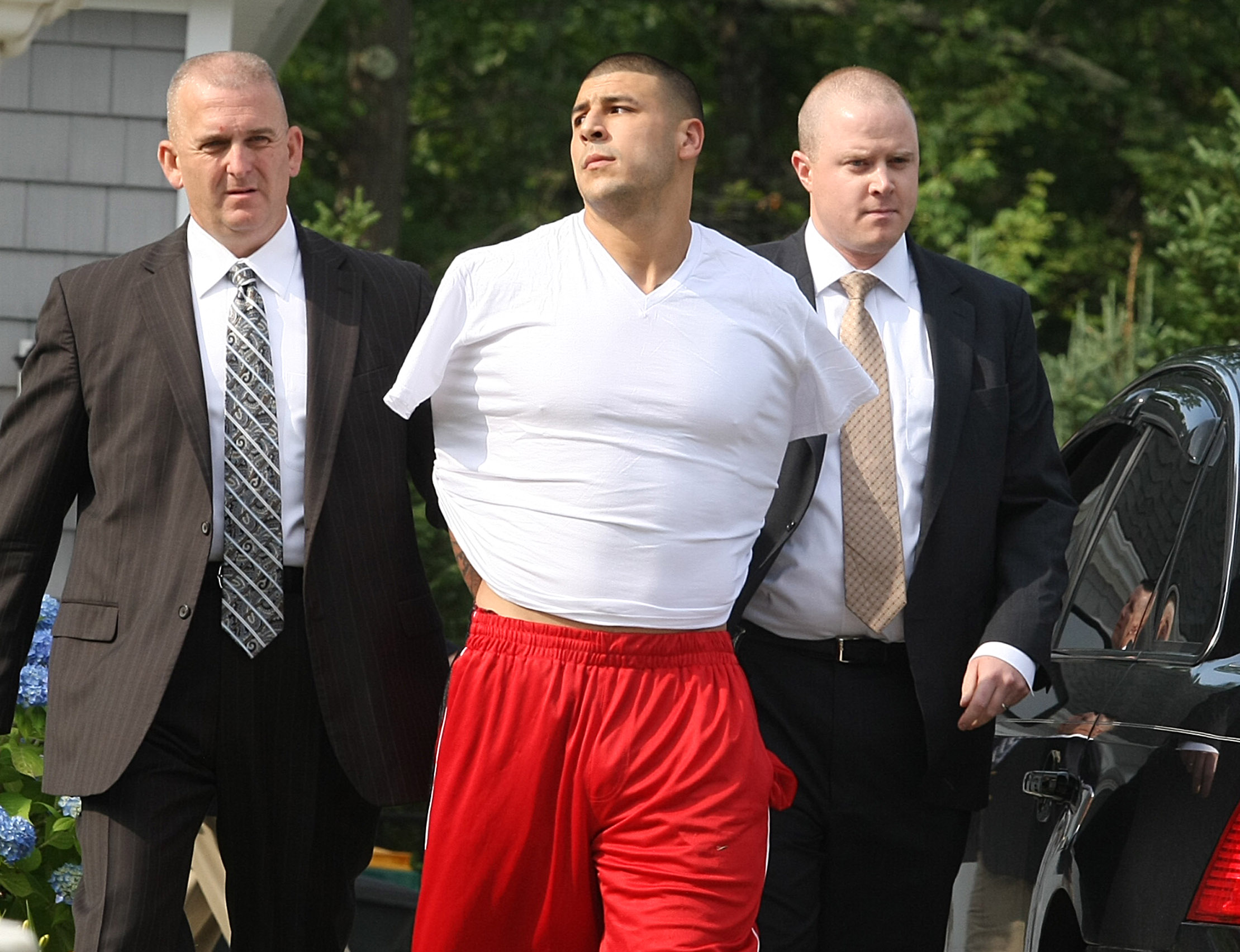 New England Patriots Aaron Hernandez is arrested and handcuffed at his home in 2013. Authorities later charged Hernandez with the murder of 27-year-old Odin Lloyd.