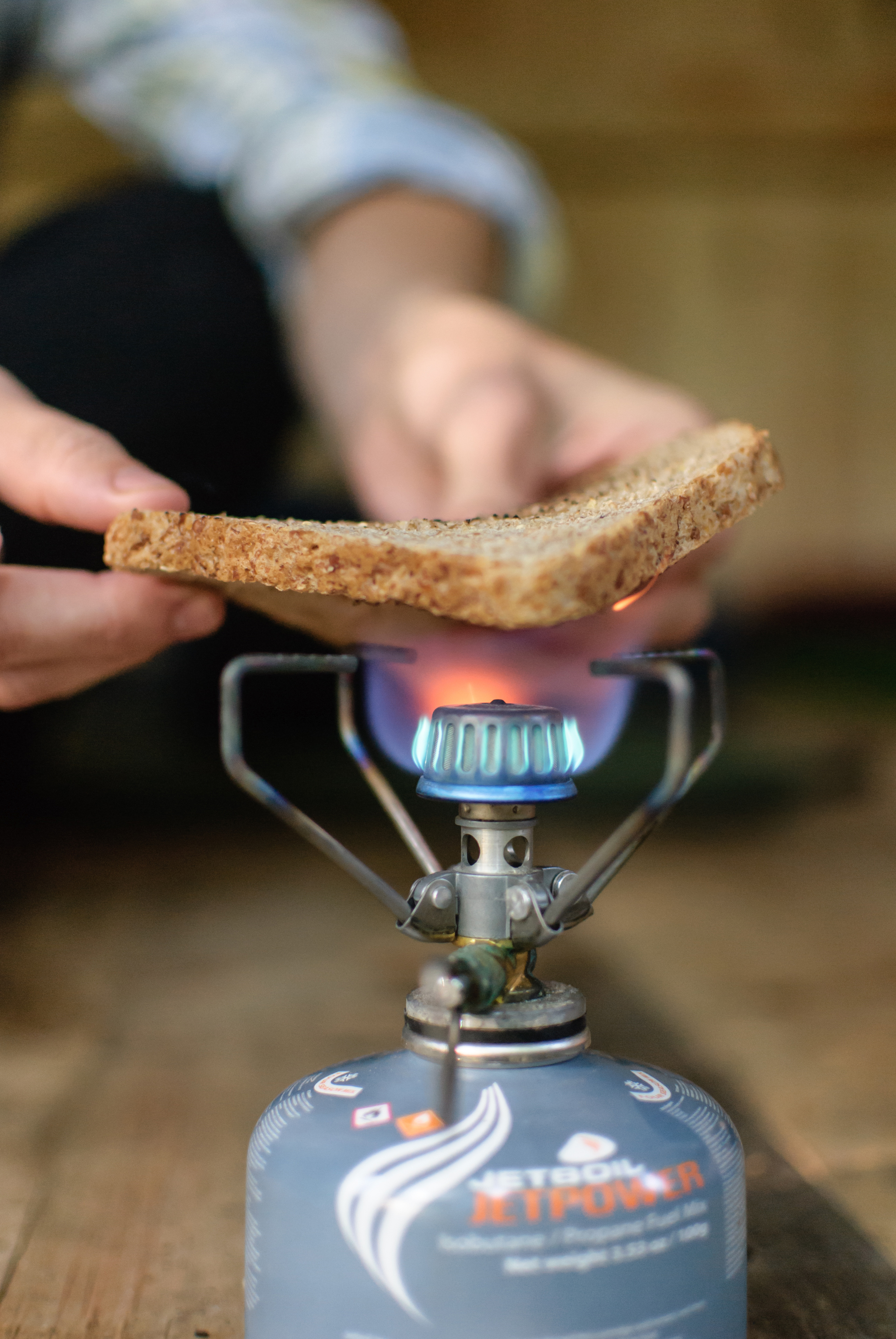 A hiker at the Old Hermit Shelter makes toast over an isobutane canister.