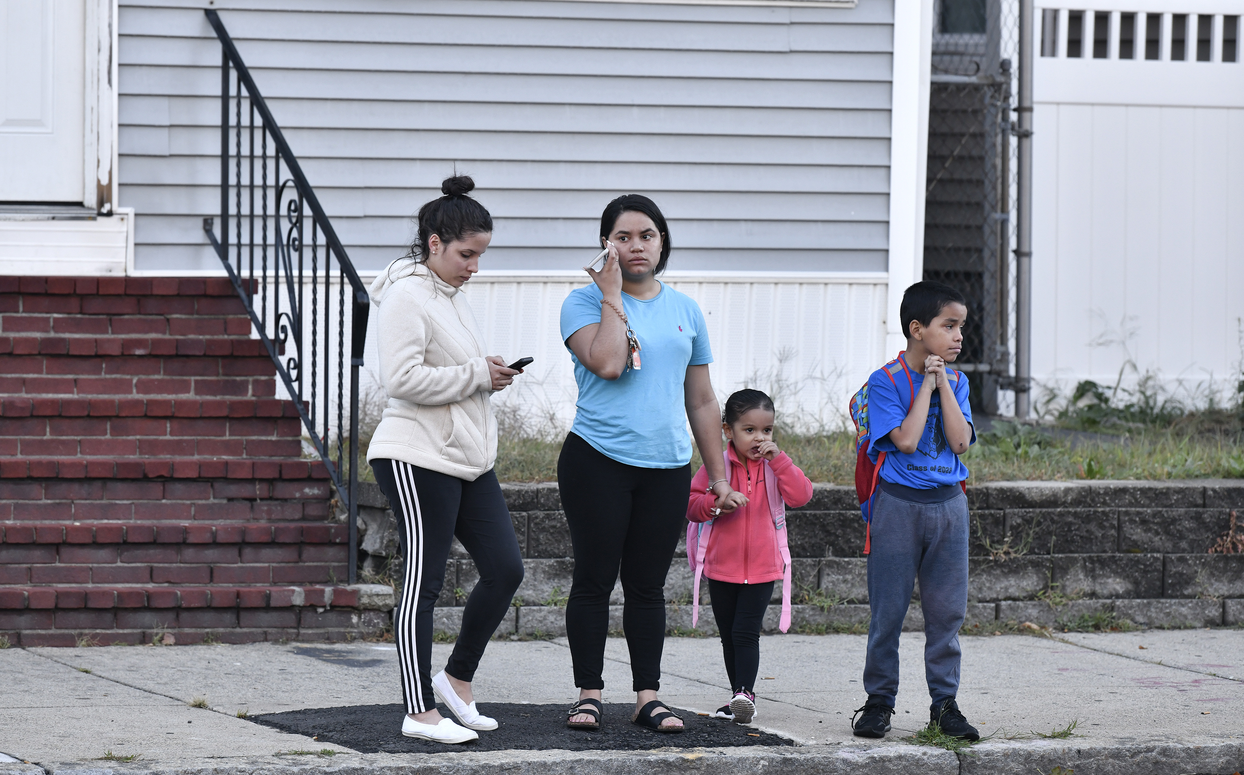 From left to right: Lizabeth Valez, Kimberly Oliveras, her daughter Kailany Torres, and nephew Luis Flores, 9, waited for a school bus on the edge of the evacuation zone on South Broadway in Lawrence.