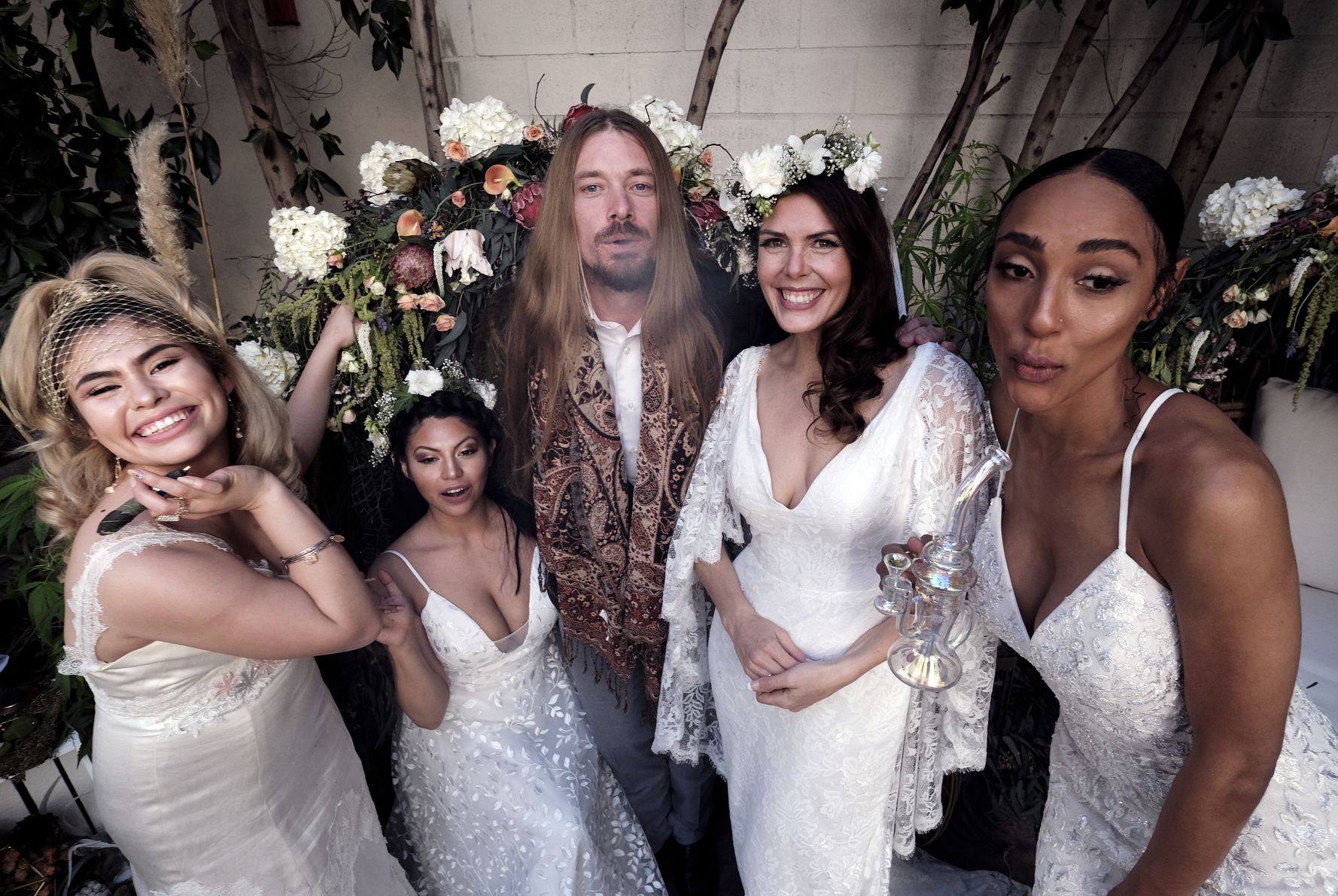 Philip Wolf, CEO of the Cannabis Wedding Expo poses with models wearing wedding dresses designed by High Vibe Bride, Simply Bridal, and David’s Bridal.