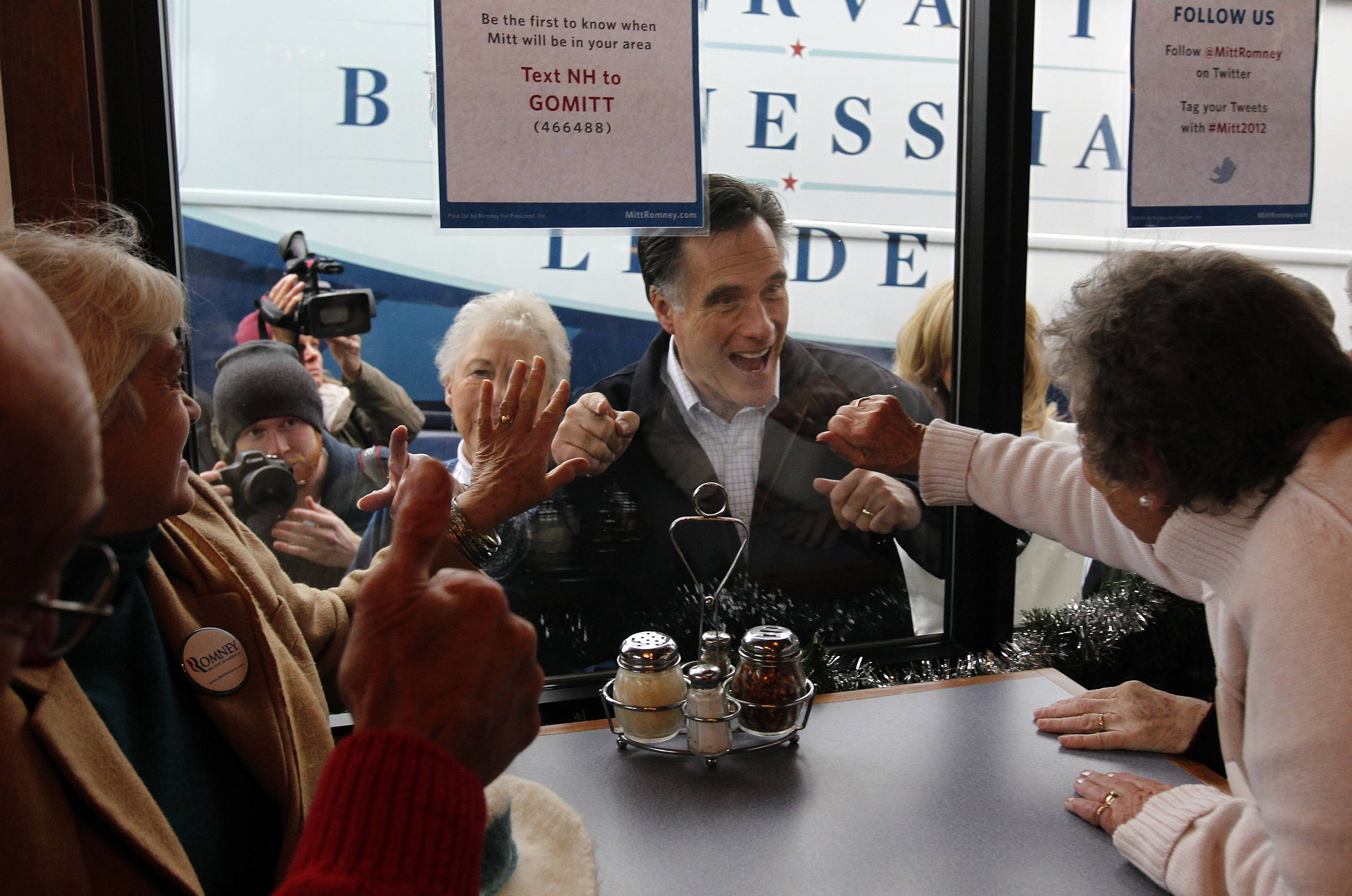 Mitt Romney waved to voters inside Village Pizza in Newport, N.H., yesterday.