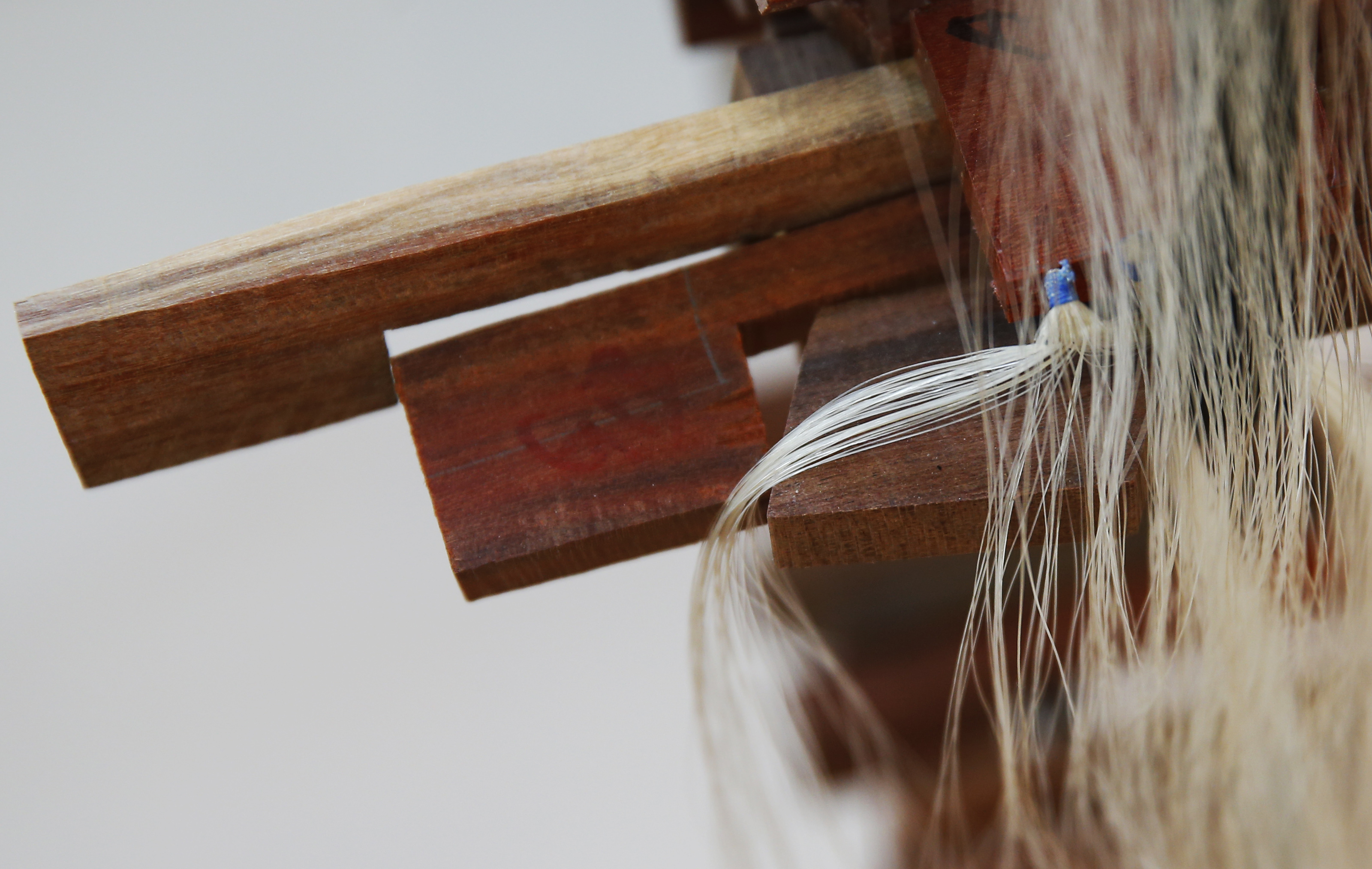 Horse hair hangs beside pieces of wood which will both be made into bows inside the home studio of MacArthur-winning bow maker Benoit Rolland.