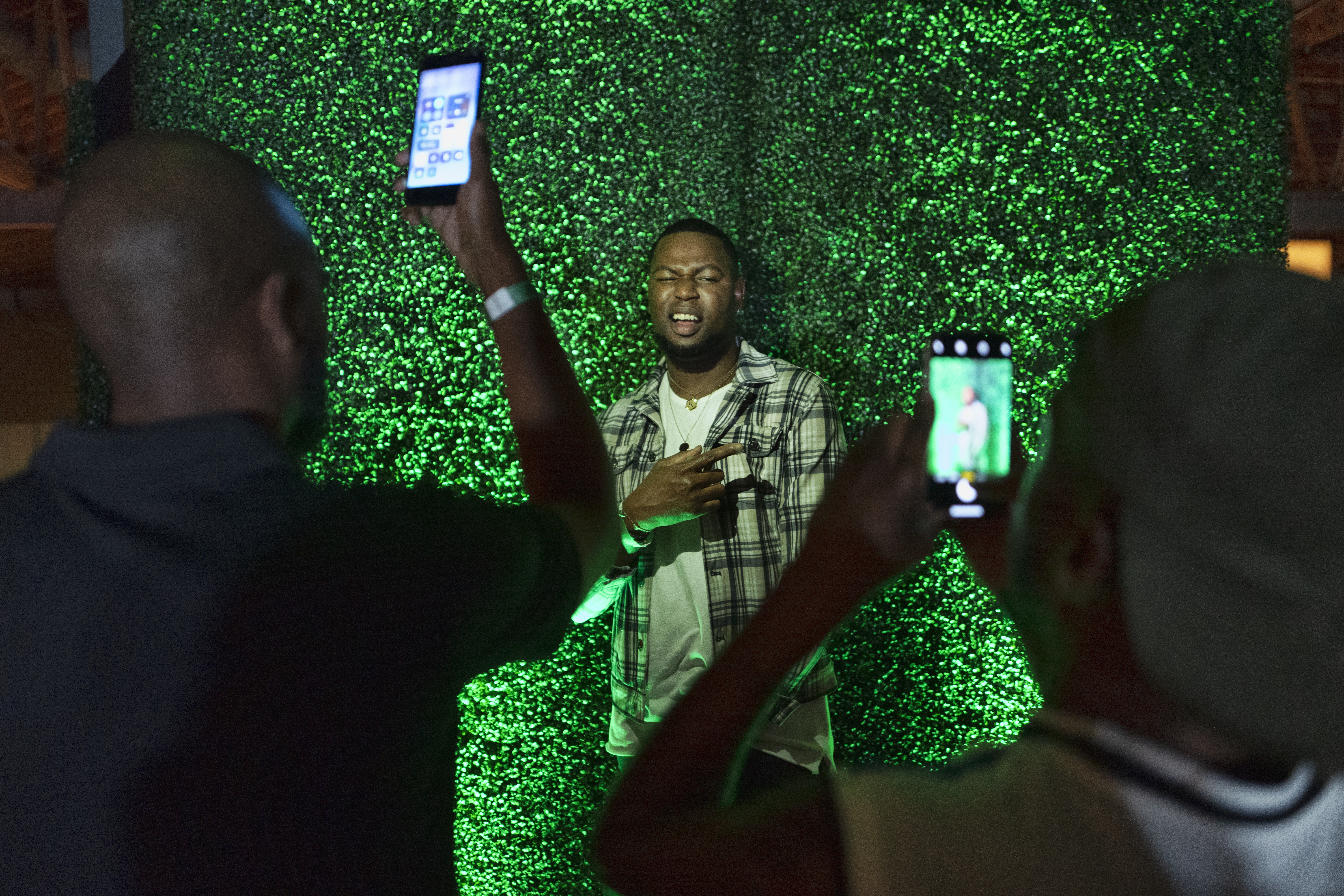 A guest takes photos in front of a grass wall.
